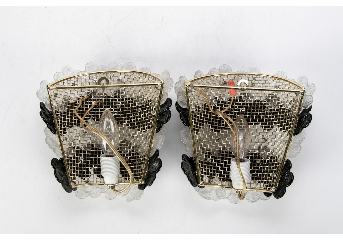 Classic Italian Mid Century Art Glass Sconce pair in striking black and white glass petals. Five bands of clear and black glass overlapping flowers. Mounted on openwork projecting curved brass frames with a single light each.  
H. 8 1/2
