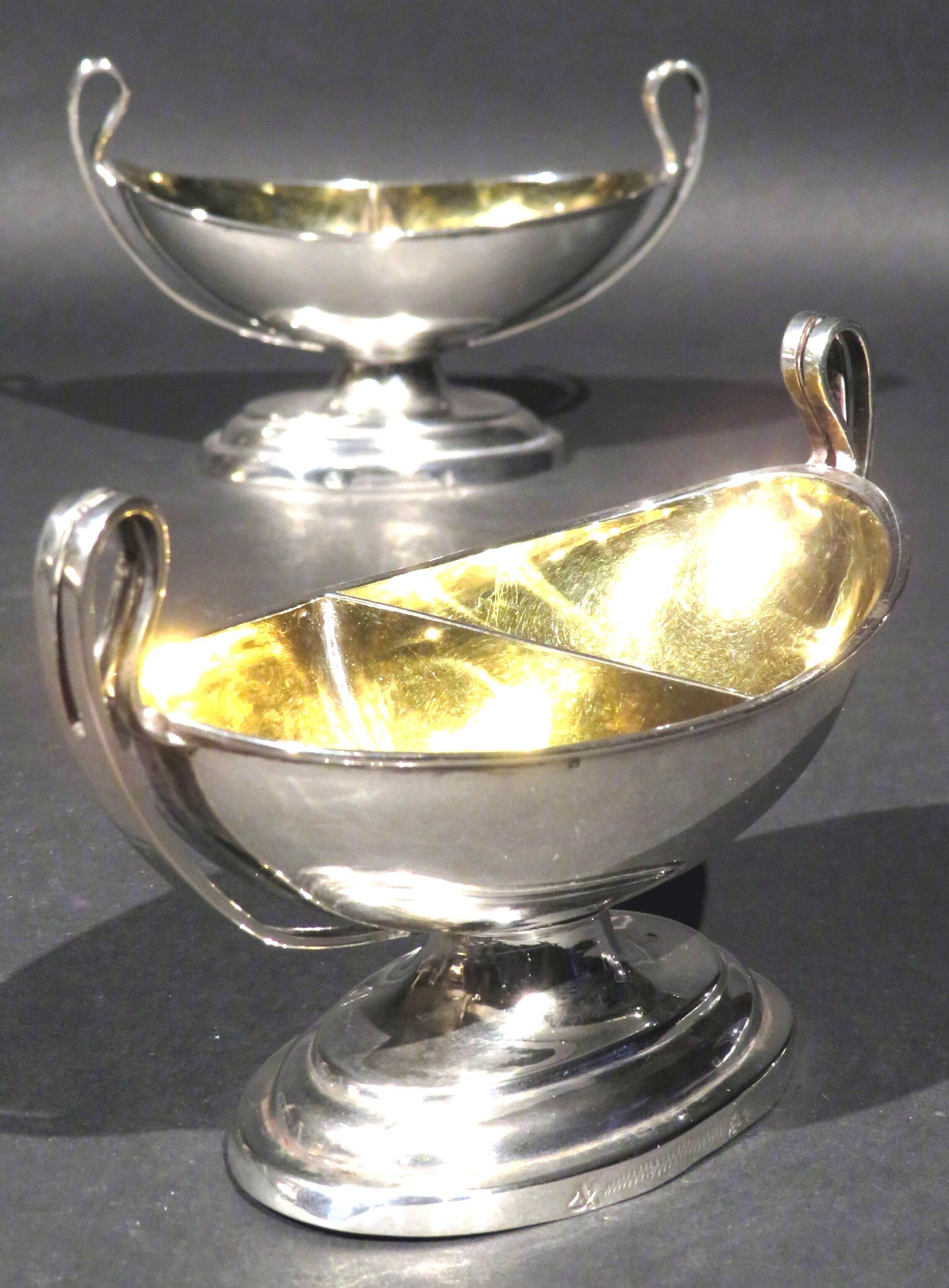 A very elegant pair of neoclassical inspired silver double salt cellars of navette form, both showing richly gilded and divided interiors and up-swept open handles, raised overall upon an oval foot bearing town marks for Leipzig, including silver