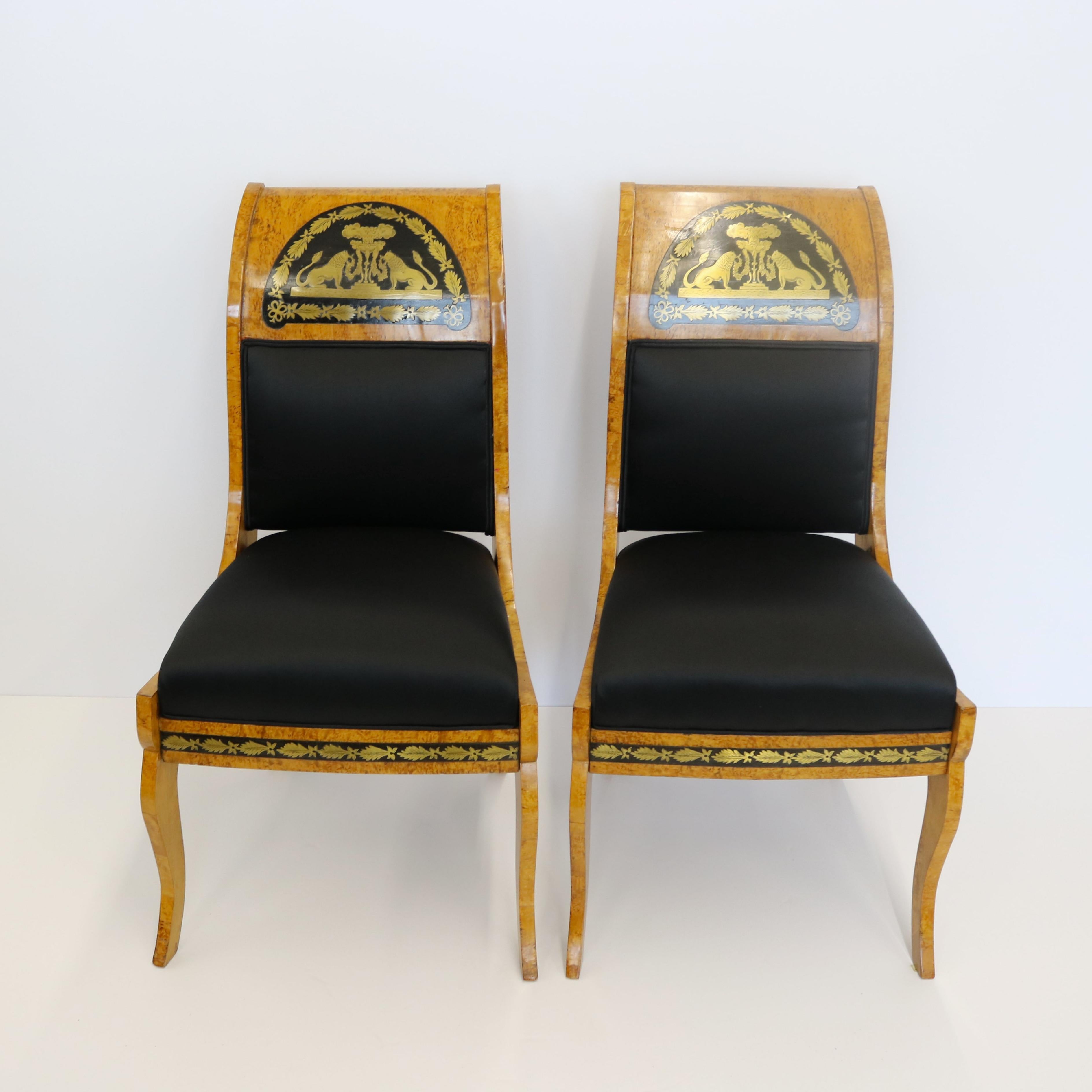 Une belle paire de chaises d'appoint Biedermeier en bouleau de Carélie et bois fruitier ébonisé.  Ils sont ornés d'un travail figuratif en laiton de Boulle vers 1850.  Chacun des dos à enroulement comporte un décor représentant des lions tenant des