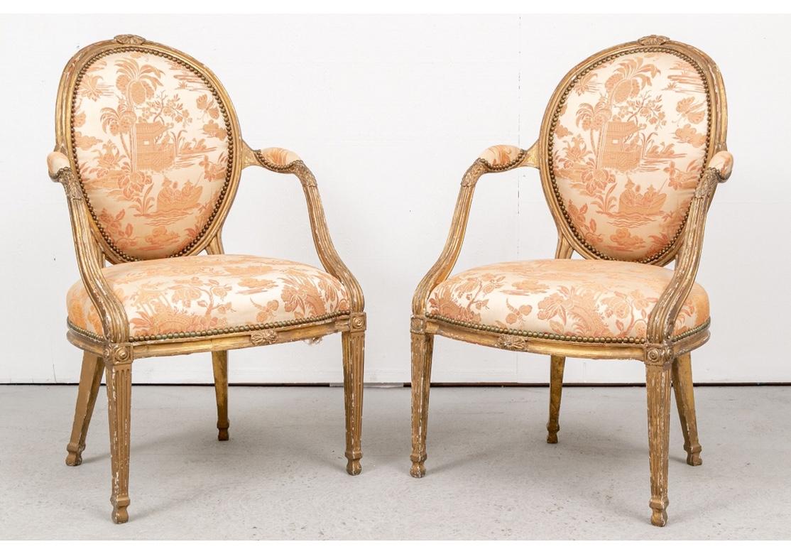 A rare and exceptional pair of George III gilt armchairs. English made in the Louis XVI style with oval backs. The carved crest rail with center rosettes, the fluted sloping arms with carved acanthus leaves on the ends. The curved seat rails with