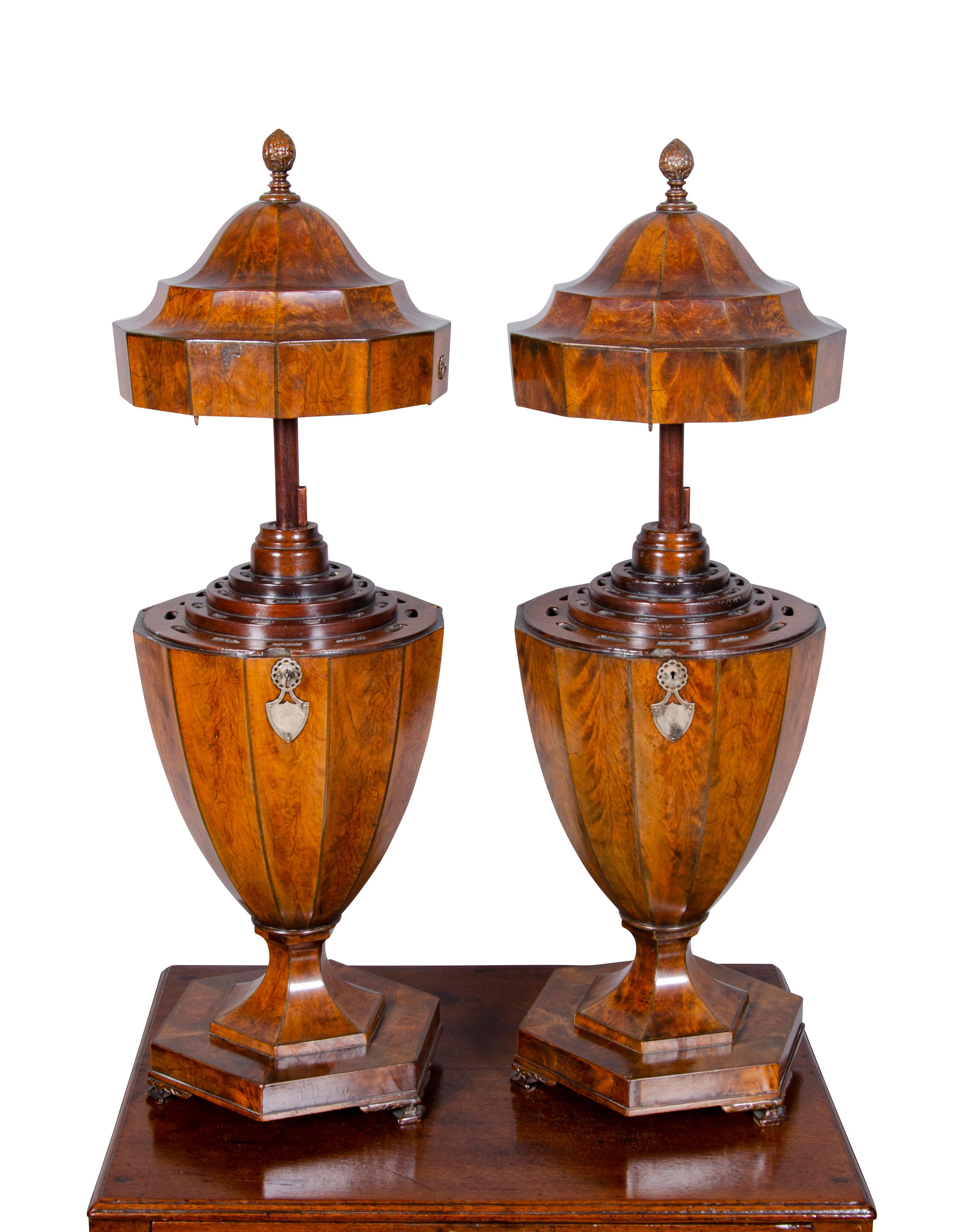 Urn form with arched cover with carved finial opening to expose cutlery slots, well figured mahogany with mellow brown color, silver escutcheons, octagonal base with bracket feet.