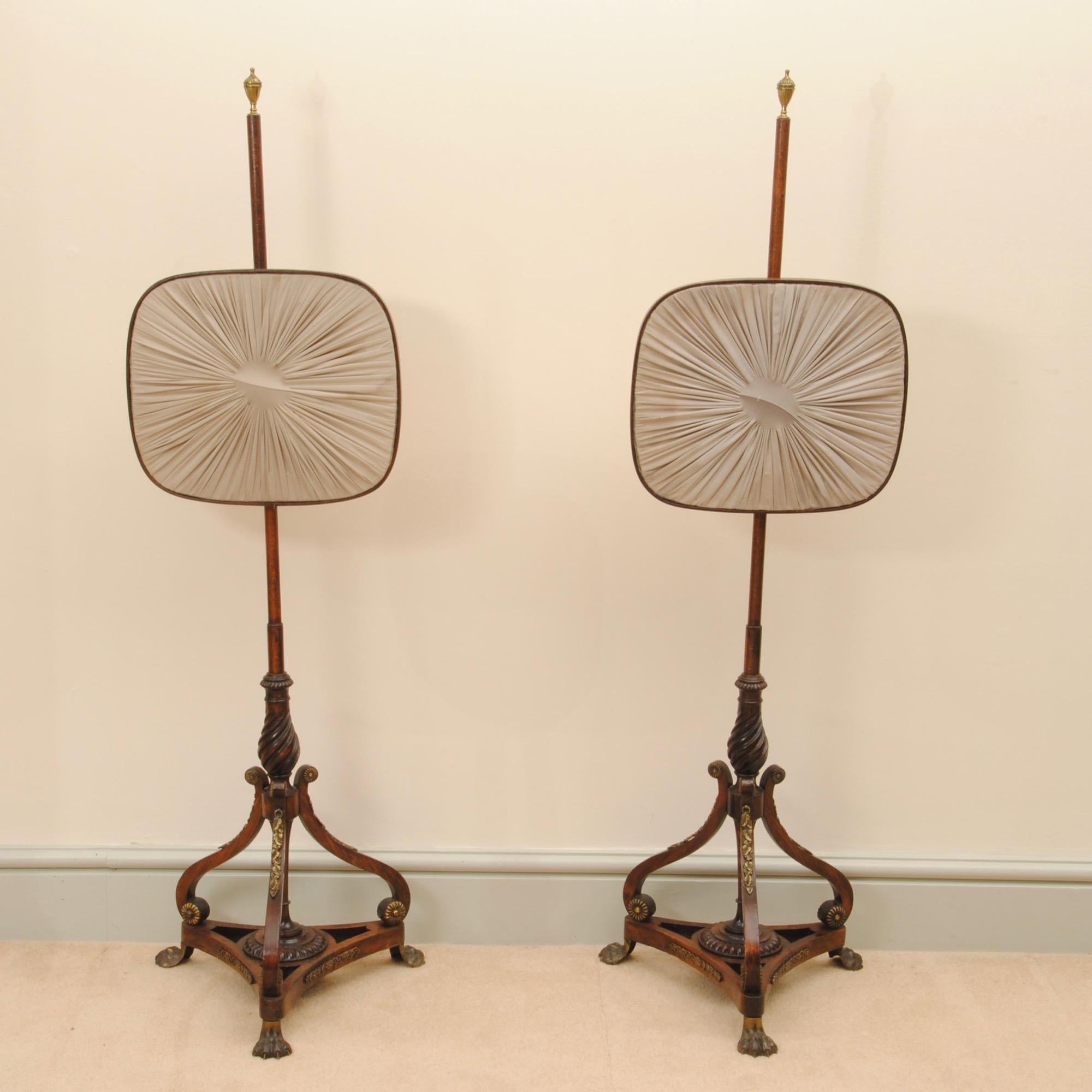 Una superba coppia di paraventi reggenti dal design elegante con applicazioni in metallo dorato sui supporti in legno di palissandro e piedi a zampa.
 