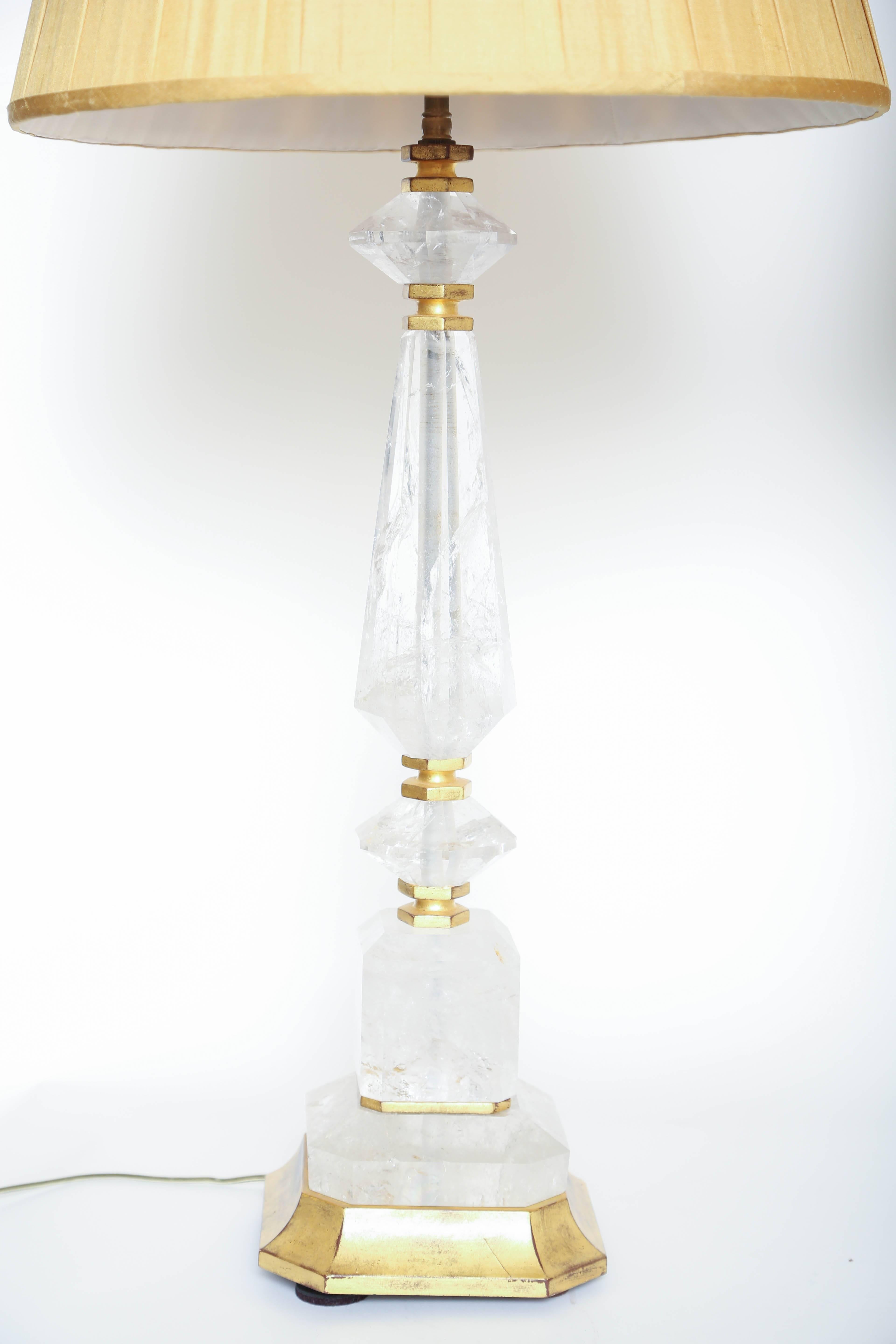 Coppia decorativa di lampade in cristallo di rocca in stile geometrico con fusto esagonale e base e accenti in legno dorato (paralumi non inclusi).