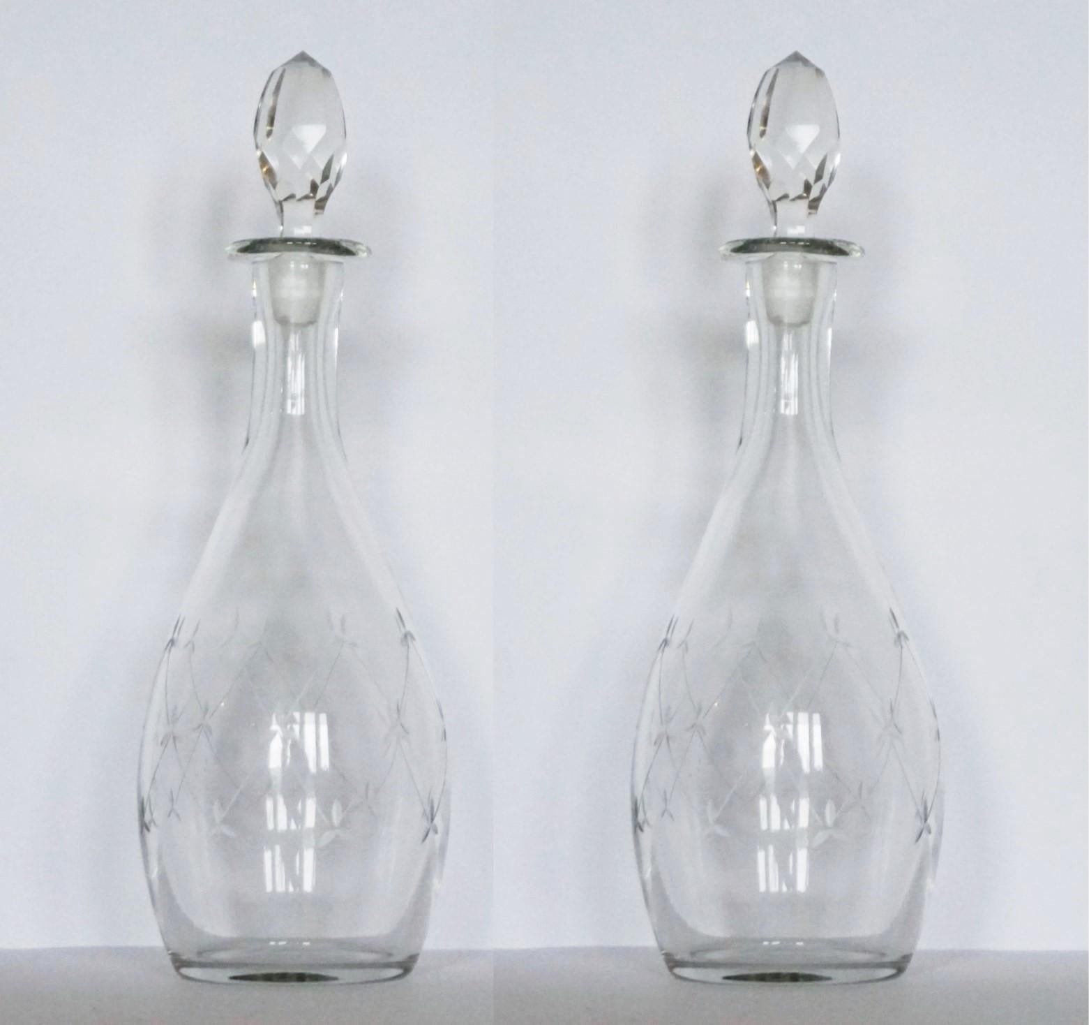 A fine pair of Victorian clear crystal tapered decanters or carafes finely hand-engraved with elegant motivs, with its original hand-faceted rock crystal tall stoppers, England, circa 1860-1870. Both decanters in very good condition, no chips or