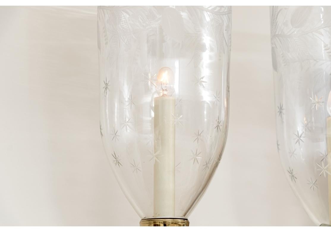 Soportes de pared en forma de concha de madera tallada pintada en color crudo con brazos gemelos de latón enrollados y velas de imitación. Las finas pantallas de cristal grabado con motivos de estrellas y vides frondosas.

Dimensiones: 25 3/4