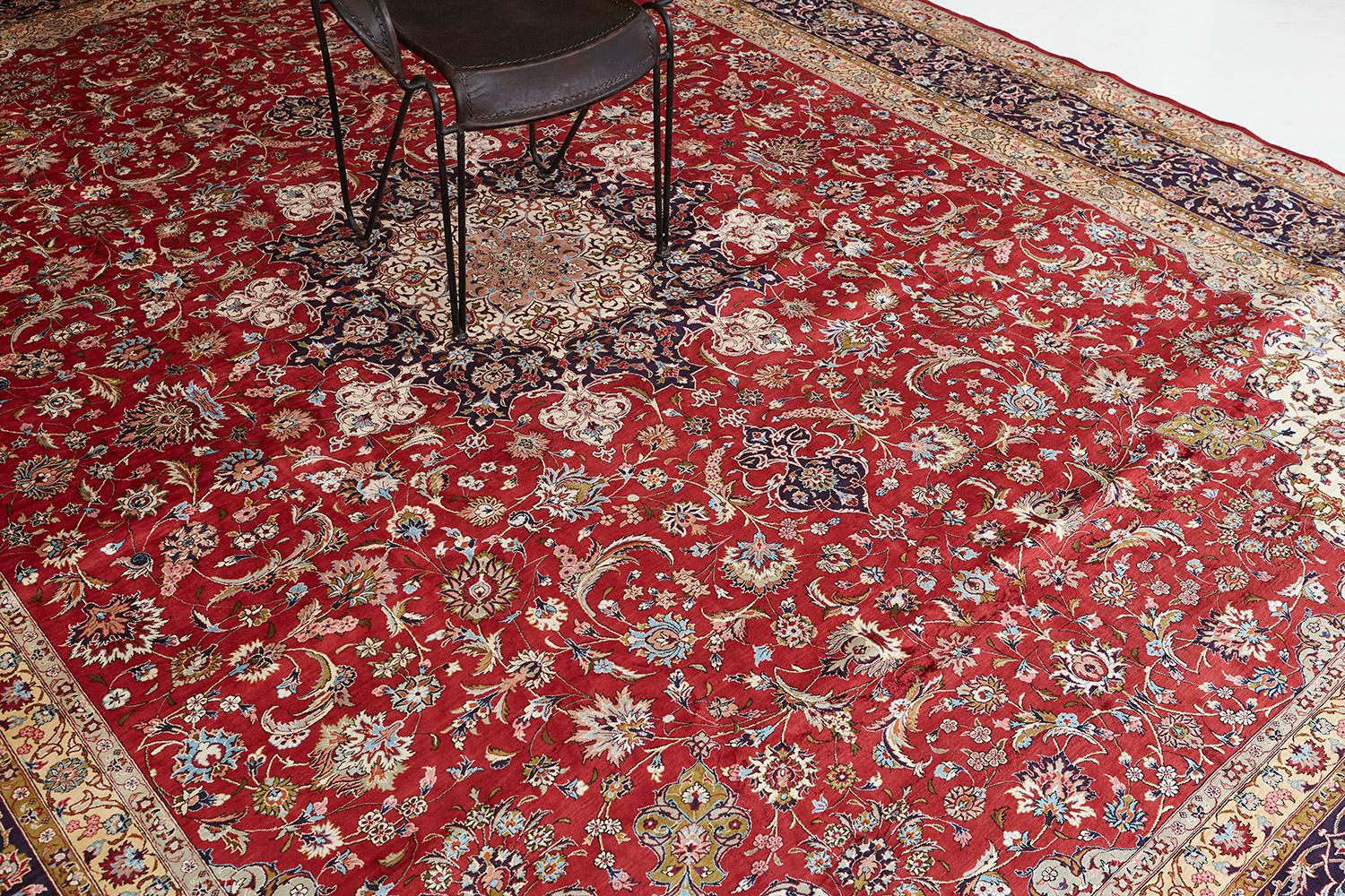 A laudable Fine Persian Tabriz rug features all the blooming elements that intensify into a prominent red field. The main border contains an all-over lattice of issuing split leaves, mini palmettes, and a delicate flowering vinery that makes the rug