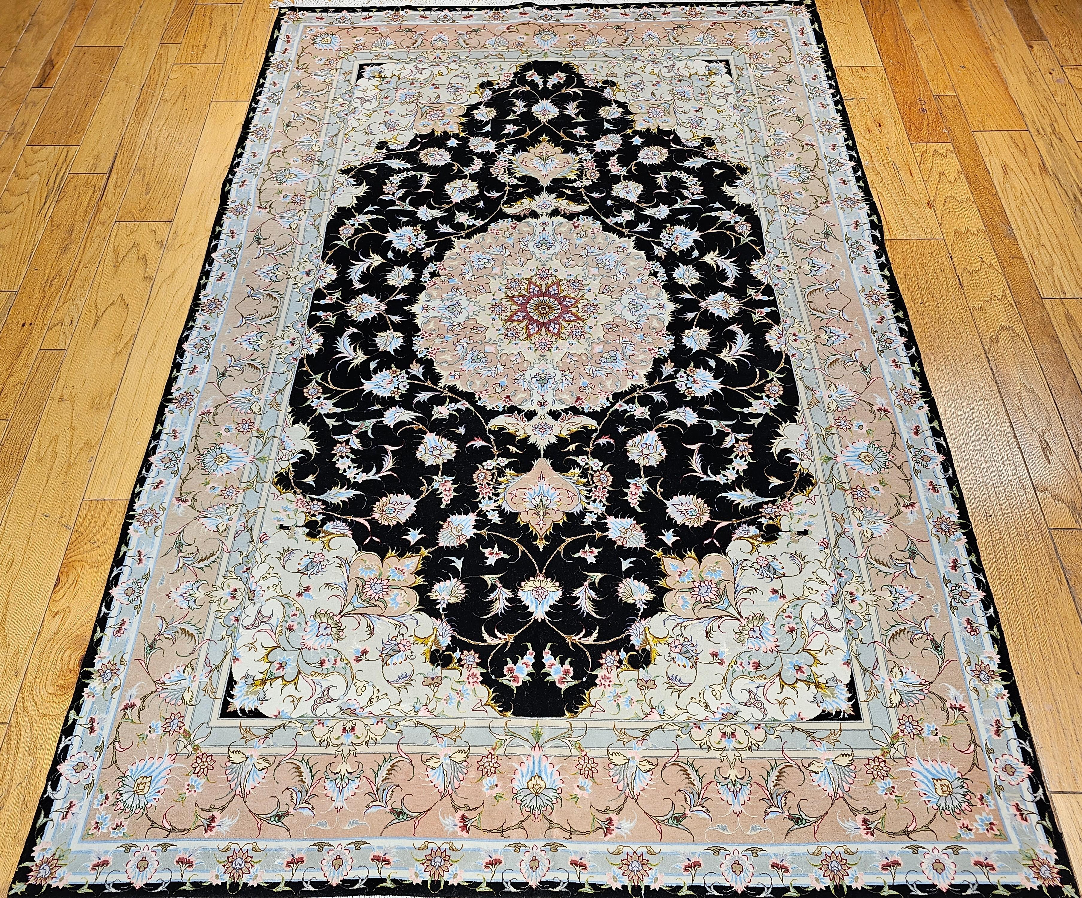 Rare and beautiful hand-knotted Persian Tabriz in a floral pattern in a black background with a brilliant color palette.   The rug has a wool pile on a cotton foundation with silk highlights.  It has a pale peach color border. The central medallion