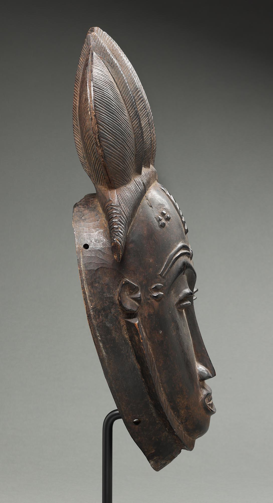 Feine Portrait-Kpwan-Maske mit hohem geflochtenem Haarmuster, dunkel bis schwarz patiniert, aus der  Baule Menschen Elfenbeinküste Afrika, ex Fearing.
Gut geschnitzte Gesichtszüge, geschwungene Schlitzaugen, offener Mund mit geschnitzten Zähnen.

Es