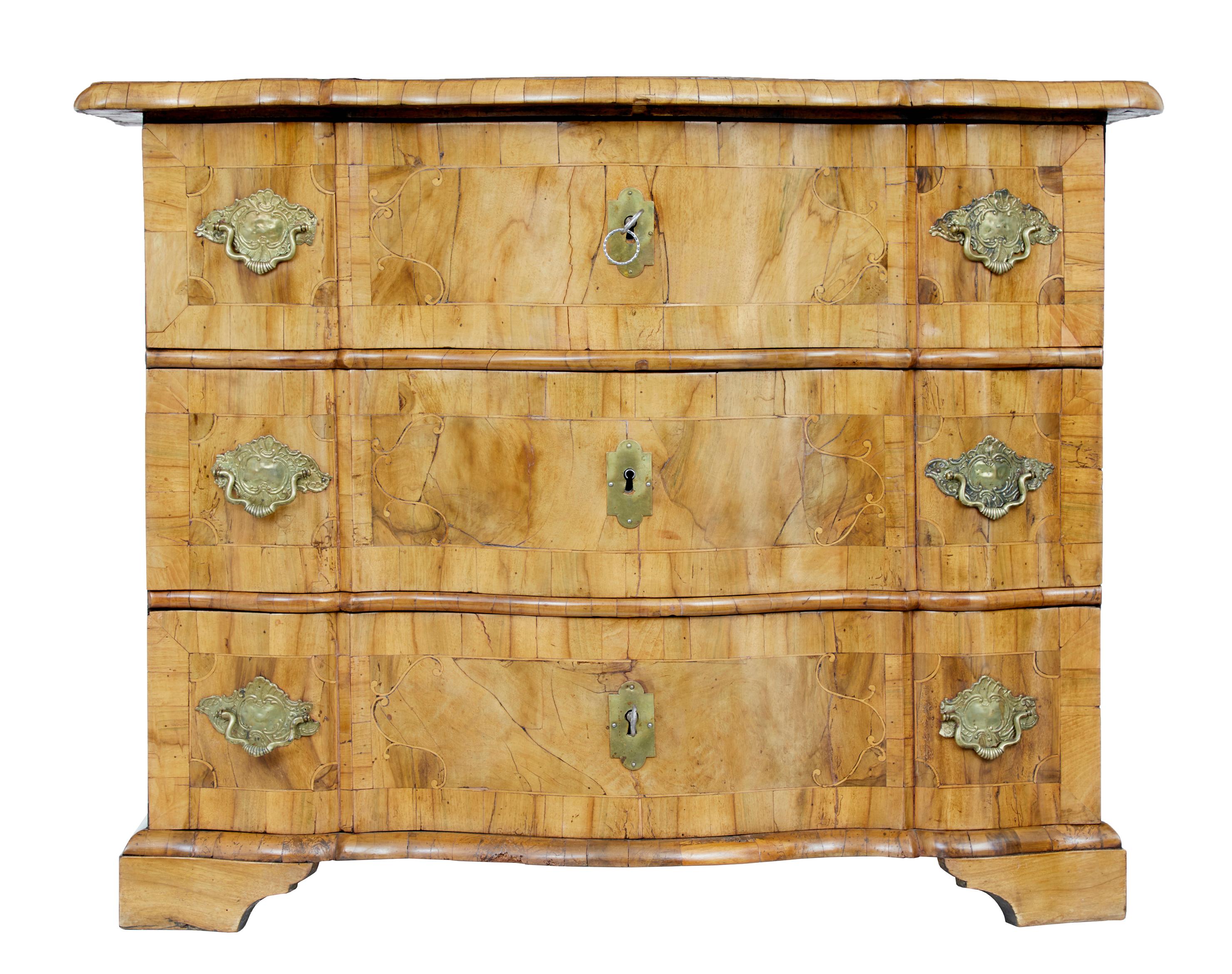 Fine quality Swedish commode, circa 1730.

Beautiful natural color which has taken nearly 300 years to develop. Serpentine over sailing top. 3 shaped drawer fronts with inlay and stringing. Top with inlaid hunting scene.

Replaced back and