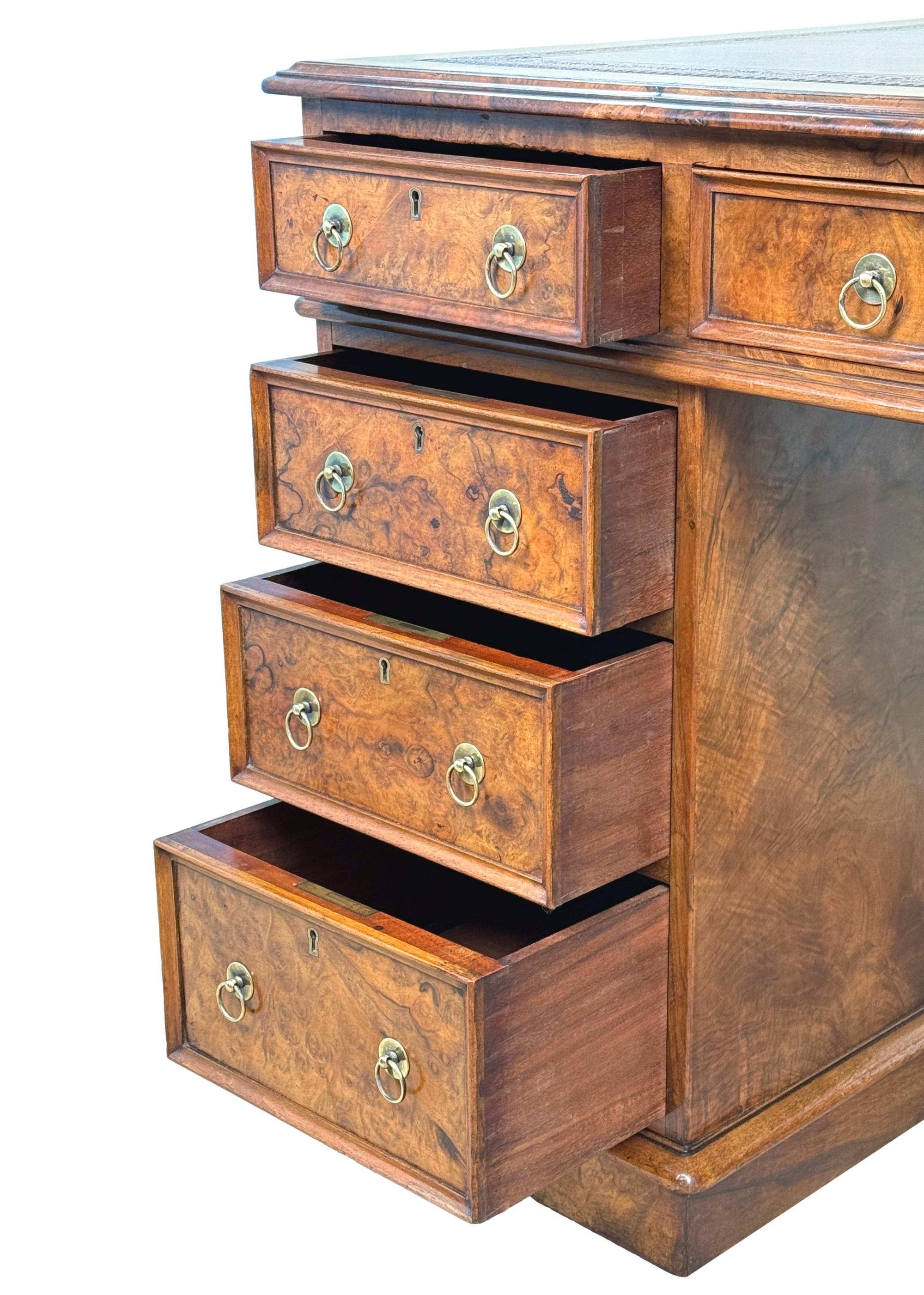 Scrivania a piedistallo in radica di noce vittoriana della met�à del XIX secolo, di buone proporzioni, con un attraente inserto in pelle dorata e decorata sul piano a fasce incrociate, sopra nove cassetti a fregio foderati in mogano, con maniglie in