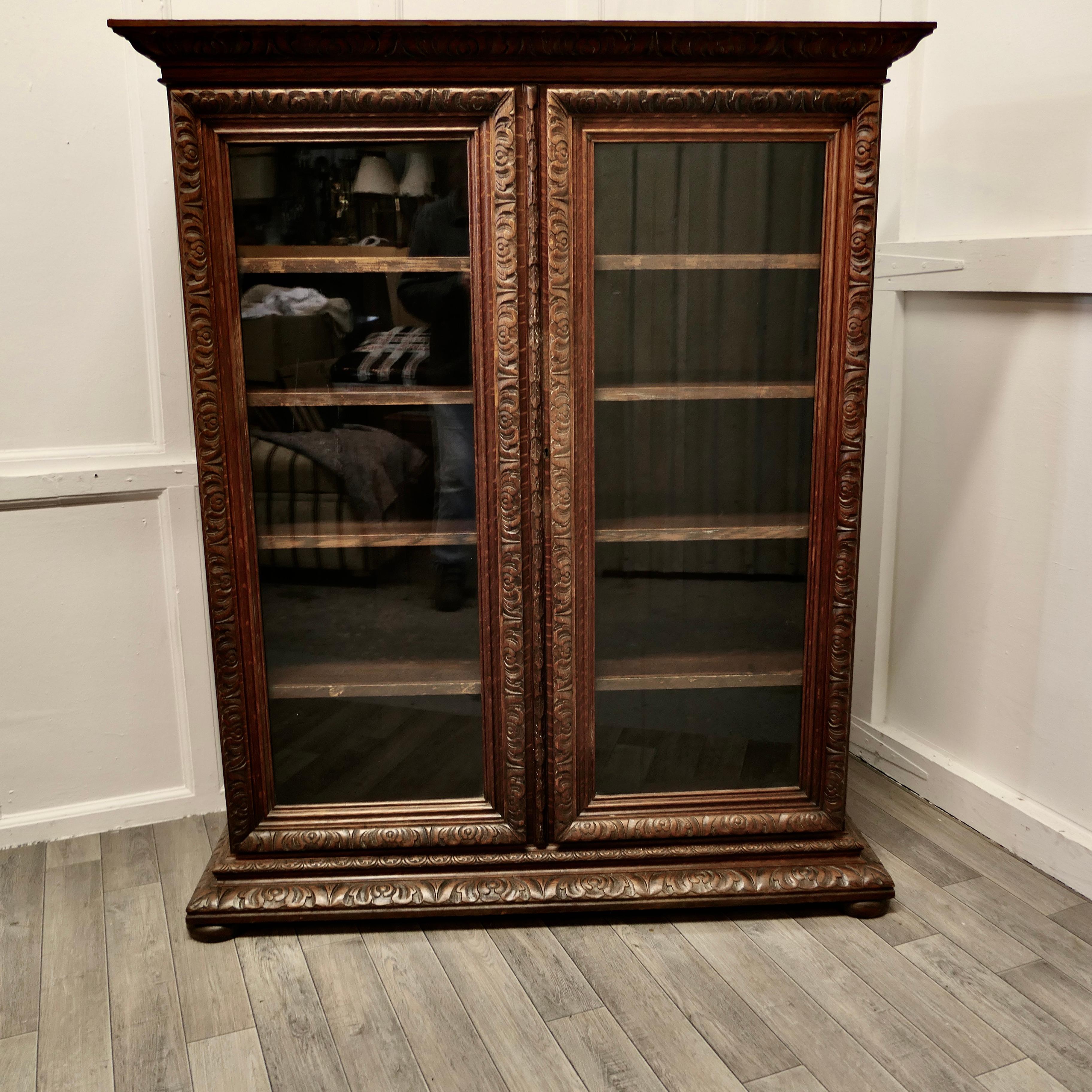 Fine Quality 19th century carved oak glazed bookcase.

This is a very attractive piece, it has 2 glazed doors which have a deeply carved border matching the top and base carving and it stands on small bun feet 
The cabinet has 4 adjustable