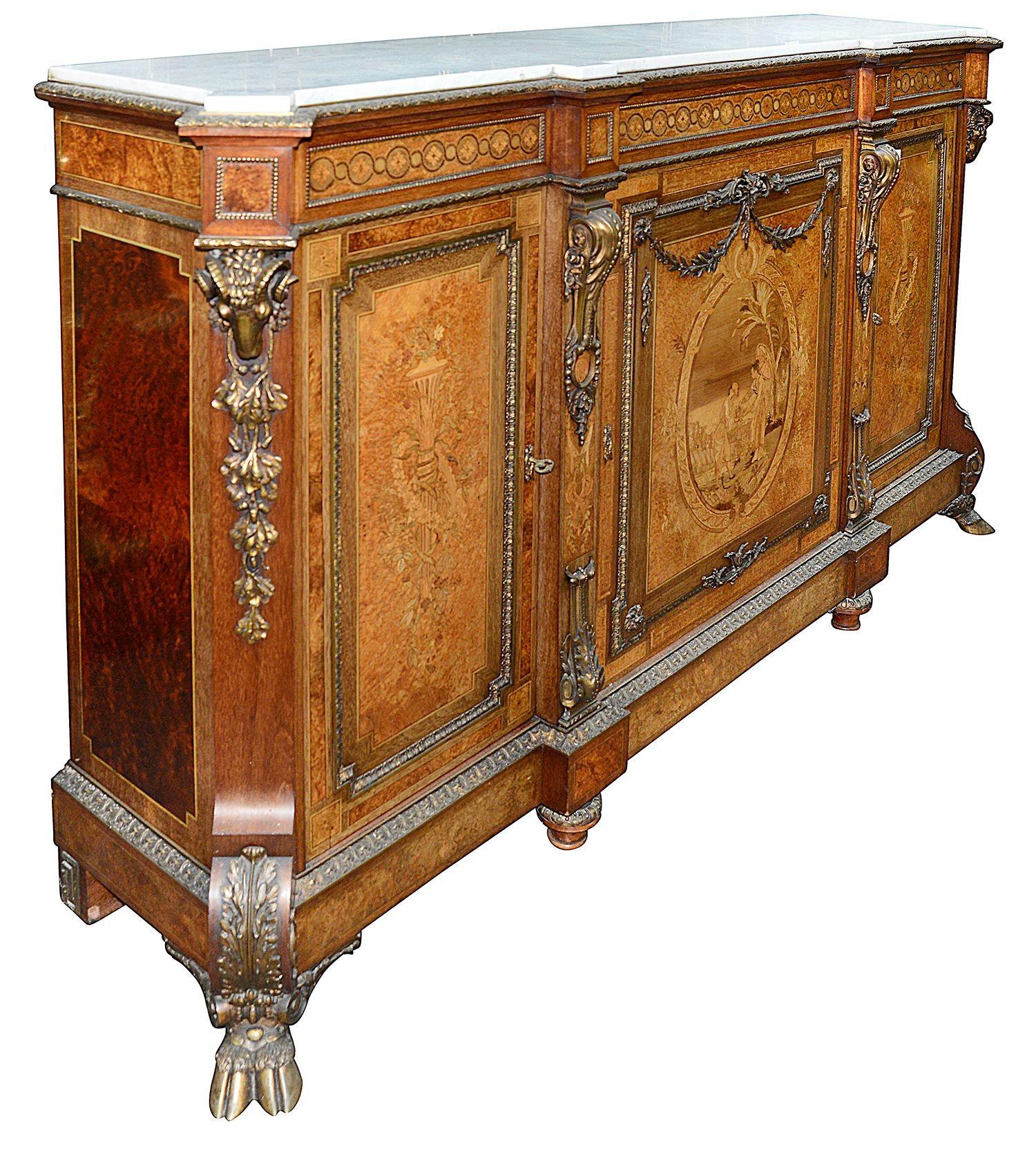 A fine quality 19th century marquetry inlaid, marble topped credenza / side cabinet. Having wonderful gilded ormolu moldings and classical Rams head mounts. Each of the three doors with neo-classical and and oriental inlaid decoration, raised on
