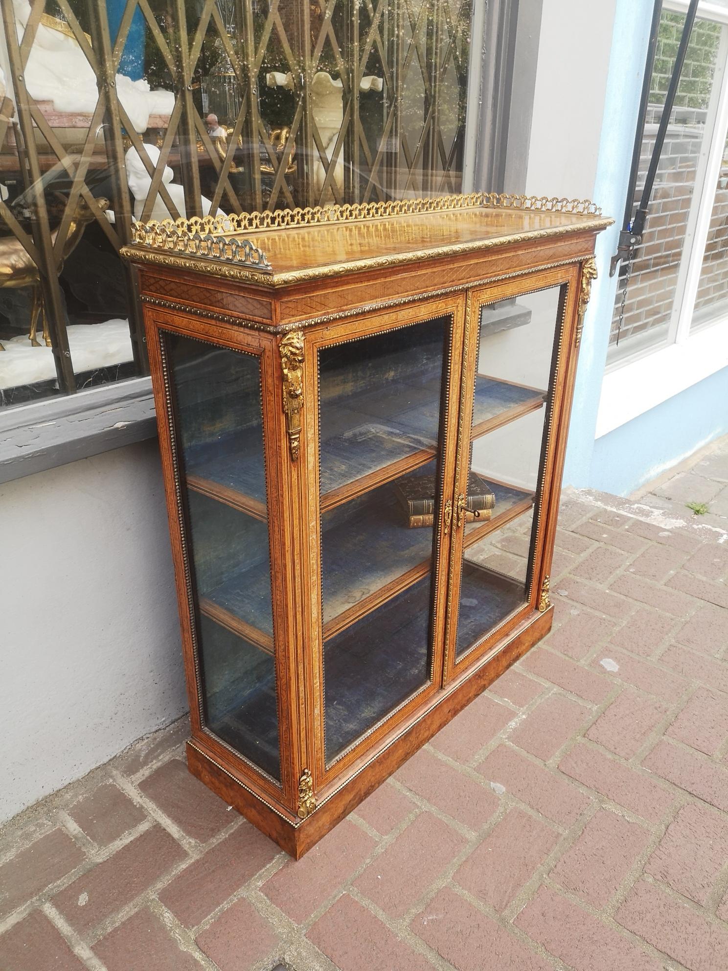 A good quality 19th century English walnut bookcase. With a bronze mounts and gallery top, inlaid with Amboyna and other exotic woods, glazed doors and sides with the original blue velvet interior.
English, circa 1860.
