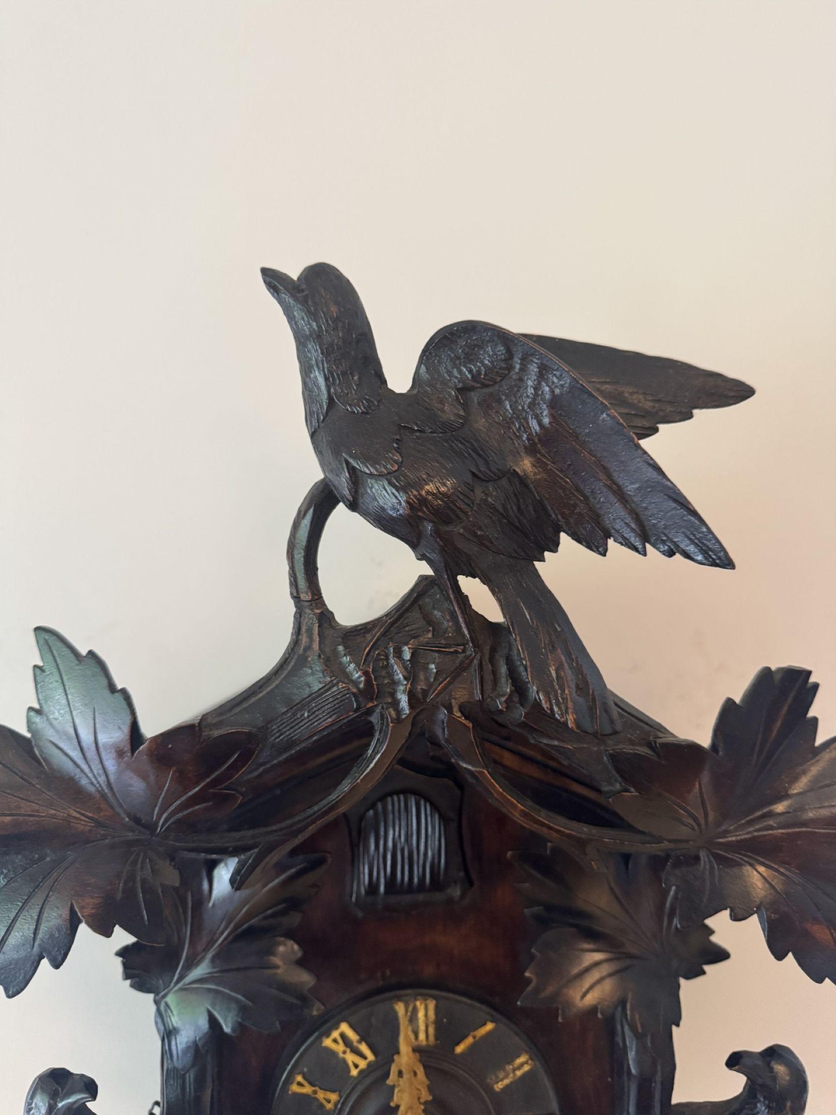 Fine quality antique 19th century Black Forest cuckoo clock having a quality carved case with carved leaves and two carved birds flanking the clock face & a carved bird to the top of the case, having a circular dial with gilded Roman numerals with