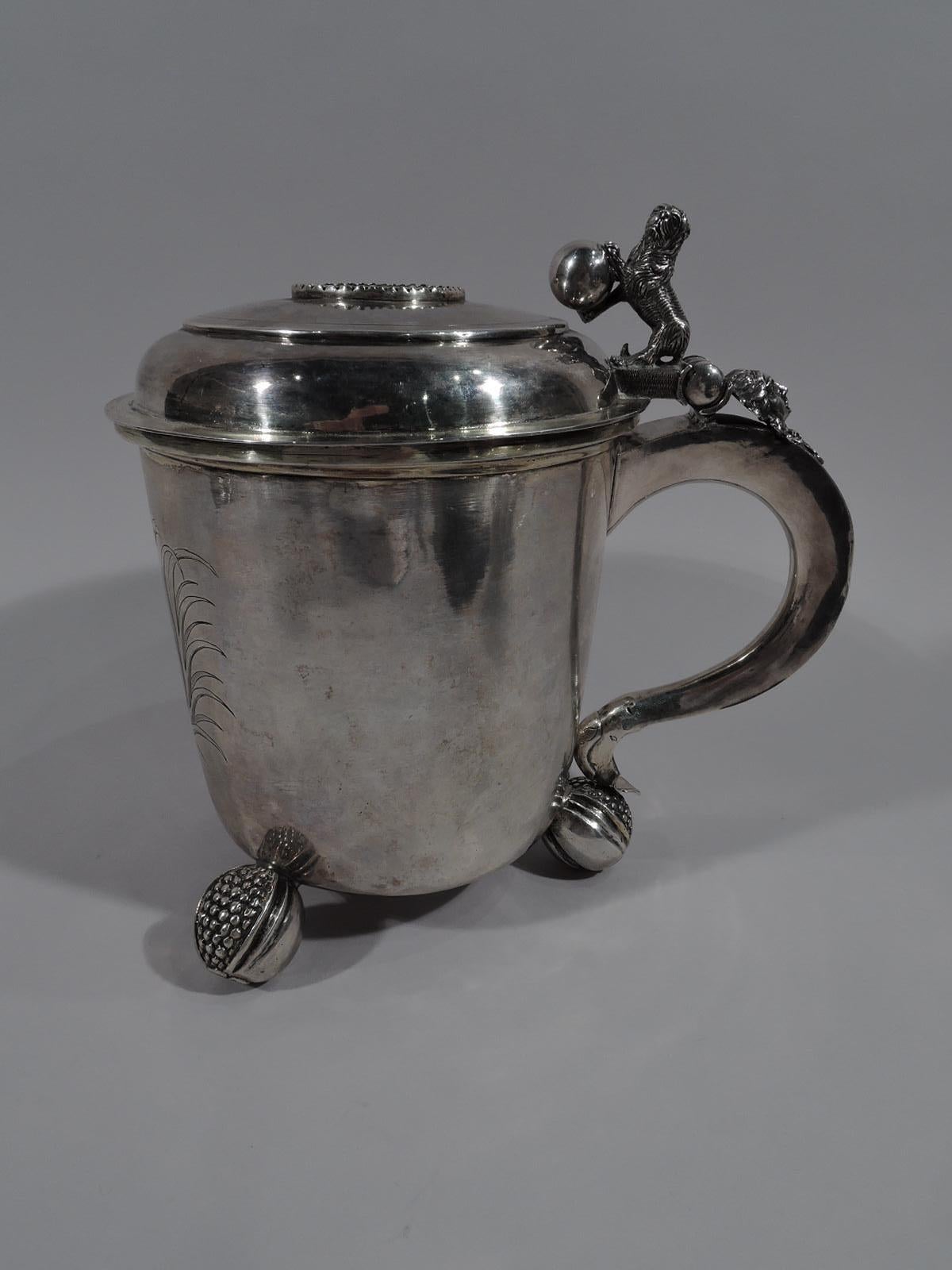 Fine quality Danish Baroque silver tankard, 1688. Drum form with 3 splayed split-pomegranate supports. Engraved armorial. Cover hinged and inset with gilt coin issued during reign of Christian IV, (1588-1648). Scroll handle with cast lion rampant