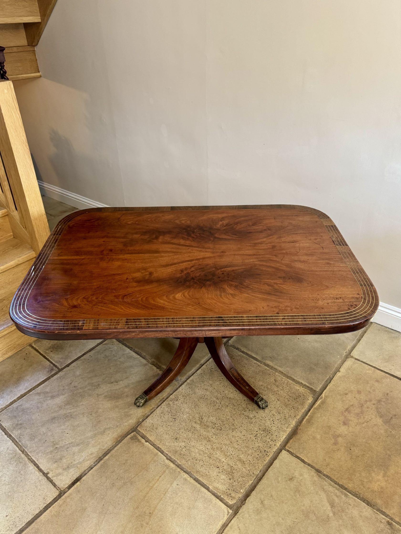 Table de salle à manger antique de qualité en acajou figuré incrusté de laiton, avec un plateau en acajou figuré incrusté de laiton soutenu par une colonne tournée, reposant sur quatre pieds sabres avec les pieds griffes en laiton d'origine.

D. 1830