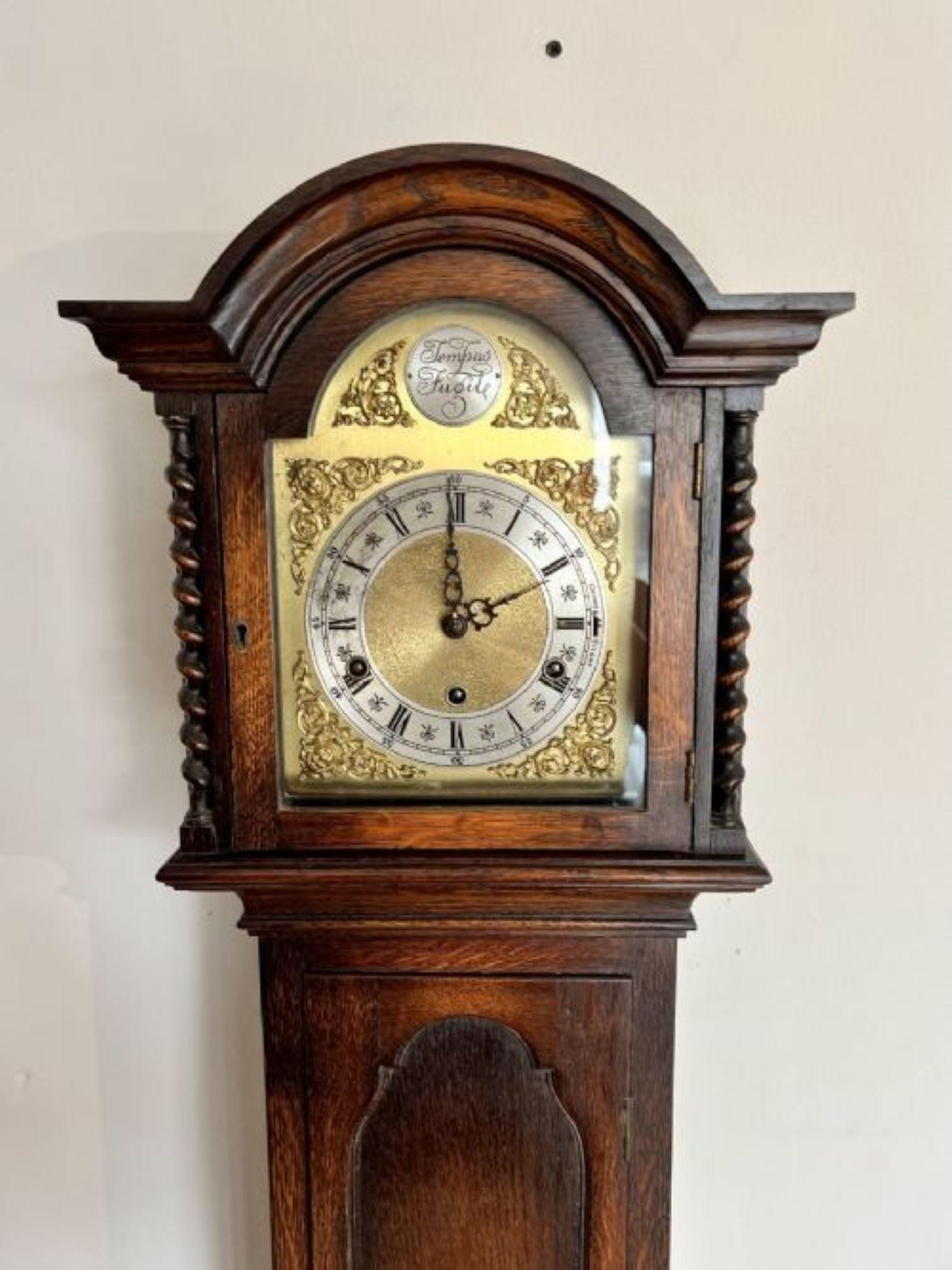 Fine Quality Antique Oak 8 Day Chiming Grandmother Clock having a superb quality oak case with carved mouldings and fine barley twist columns, quality square feet with an ornate dial and a arched brass face with ornate spandrels and inscribed