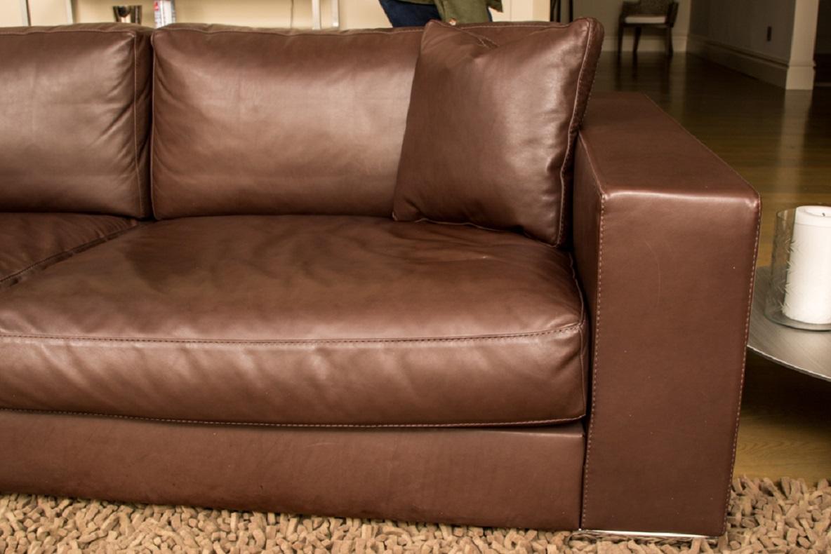 Contemporary brown leather sofa by Rivolta, Italy, in dark brown leather with fine stitching, mounted on cylindrical metal feet. With toss pillow. 

Condition: Gently used condition with minor signs of use and wear.