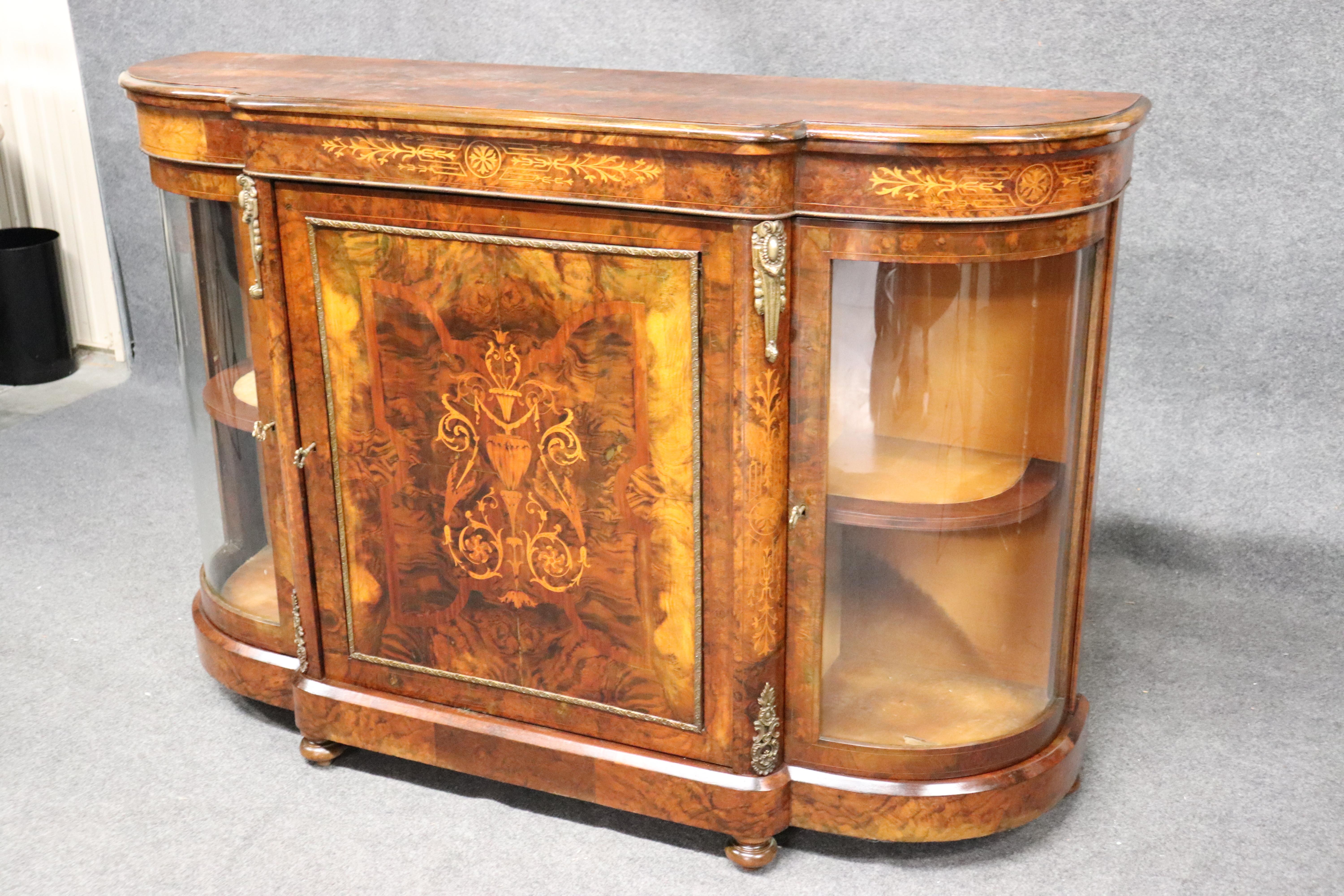 This is a fine English inlaid burled sideboard with vitrines at each end for display, circa 1870. The condition is better than the photos can show. The sideboard dates to the 1870s and is absolutely gorgeous with rich looking inlay and wood quality.