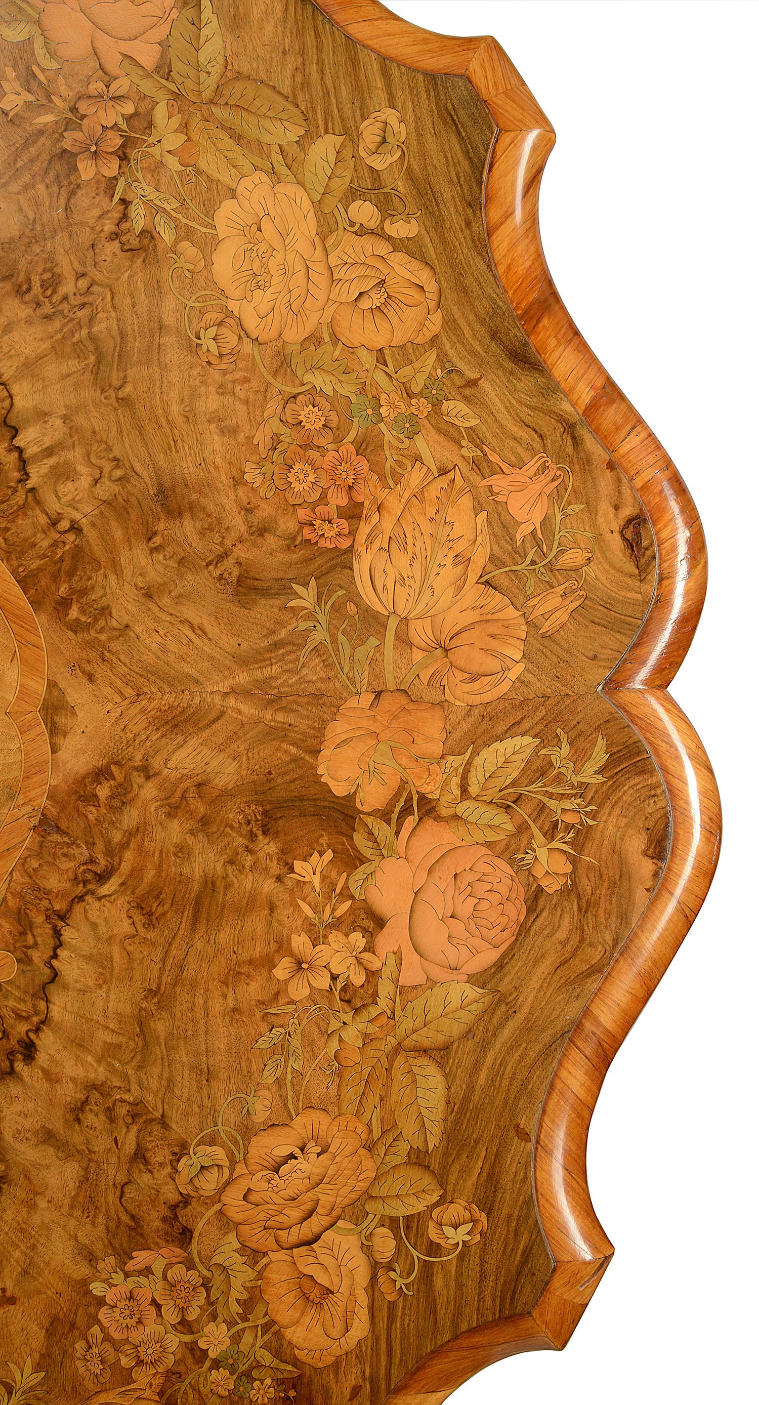 A fine quality 19th century walnut marquetry inlaid center table. Having wonderful burr walnut veneers with inlaid floral garlands around and to the center, shaped edging and raised an elegant scrolling tripod base.