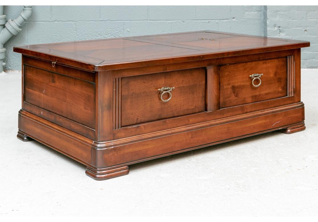 Une table de cocktail de très bonne facture, teintée dans la masse, avec des portes relevables qui permettent de ranger des jeux, des livres ou des bouteilles. Un grand tiroir accessible de chaque côté, des poignées de style nautique sur les portes