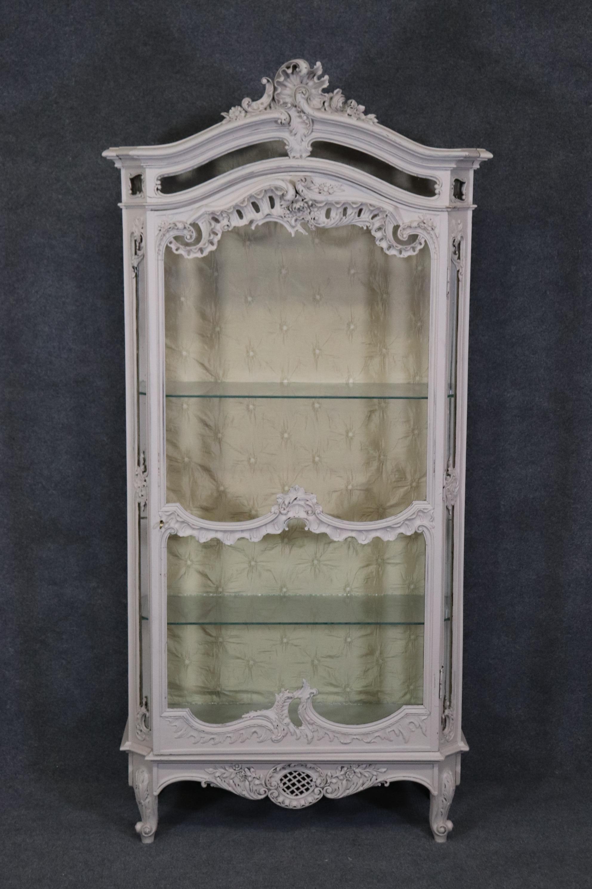 This is a beautiful creme painted Louis XV French-made Vitrine or china cabinet. The cabinet has been painted in a cool creme color and has a beautifully quilted style upholstered back. The piece is ready to take home or have delivered today and