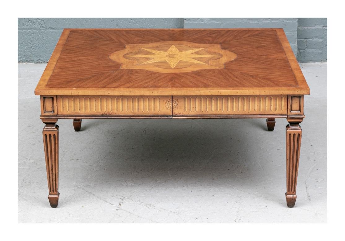 A fine and very decorative Cocktail Table in the style and manner of Alfonso Marina. A square cocktail table with an inlaid compass rose within a quatrefoil motif on a veneered top. The cocktail table with cross-banding and four frieze drawers