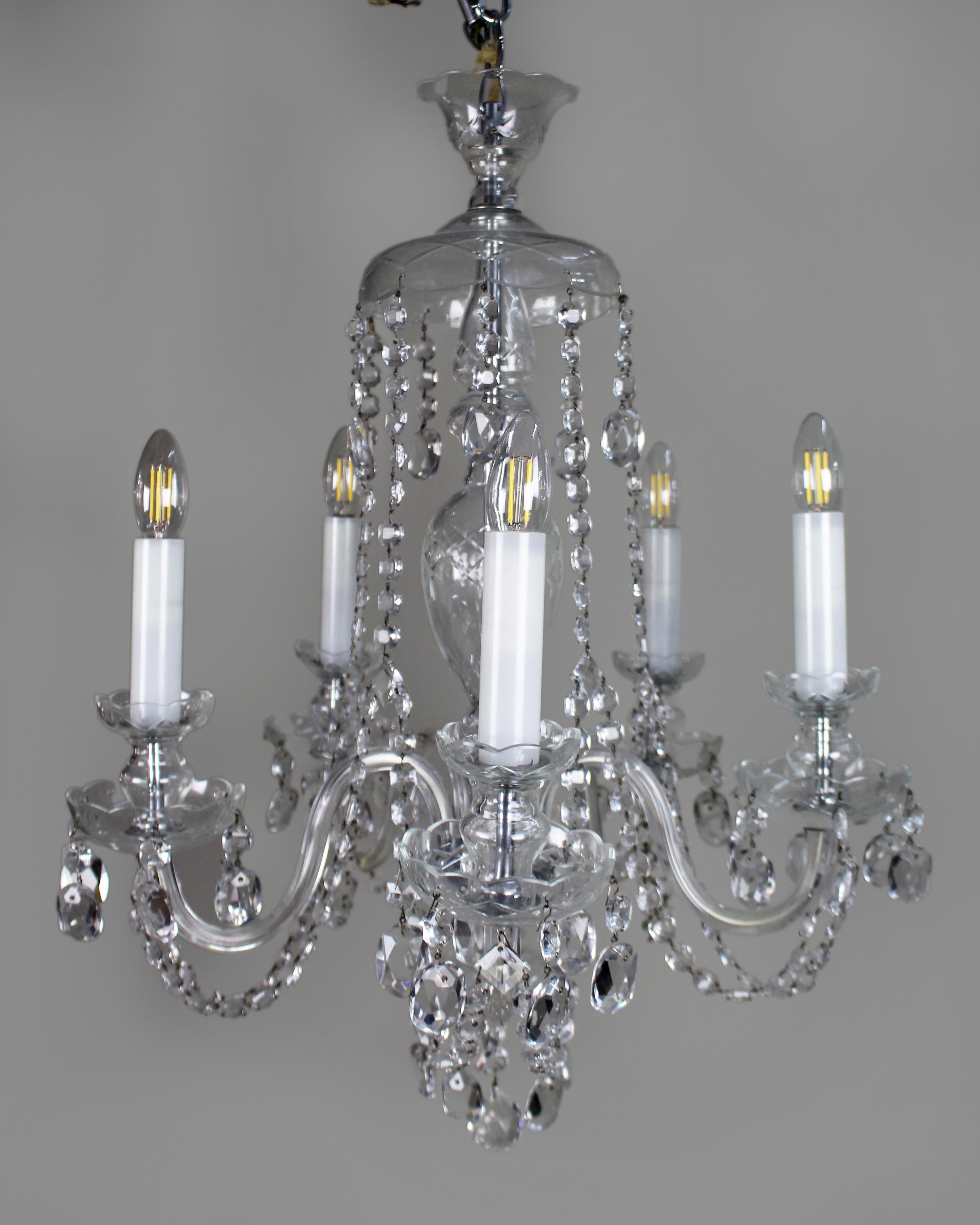 Five-Arm French Cut Glass and Crystal Chandelier, Mid-20th Century
A finely crafted mid-20th century French chandelier of elegant form, dressed throughout with hand-cut crystal drops and faceted glass swags.

Comprising five curving glass arms with