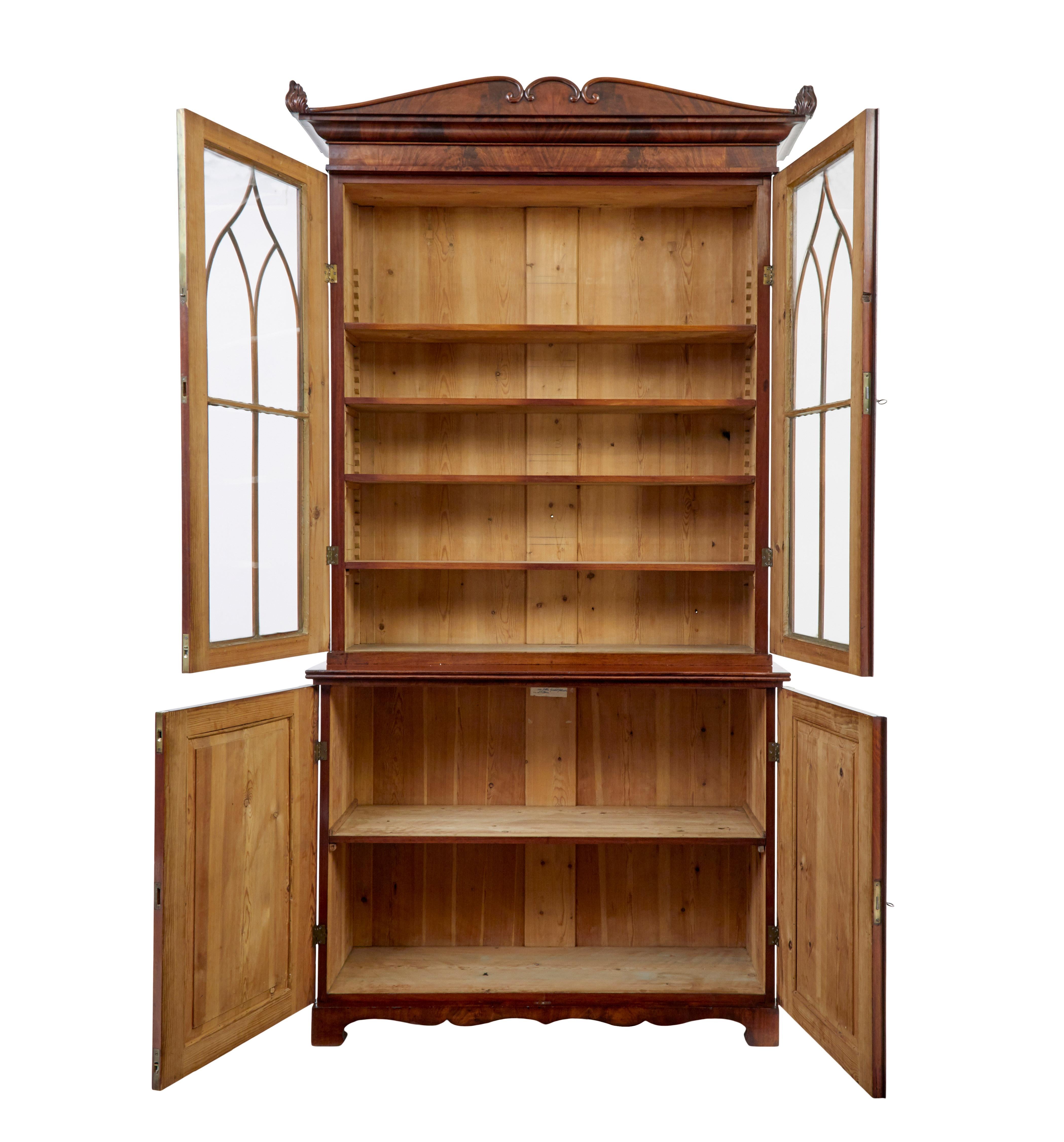 Fine example of a regency period bookcase circa 1820.

Very much in the manor of Thomas Hope.  Matching flame mahogany veneers from top to bottom.  Comprising of 3 sections, lower cabinet, glazed cabinet and removable cornice.

Shaped cornice with