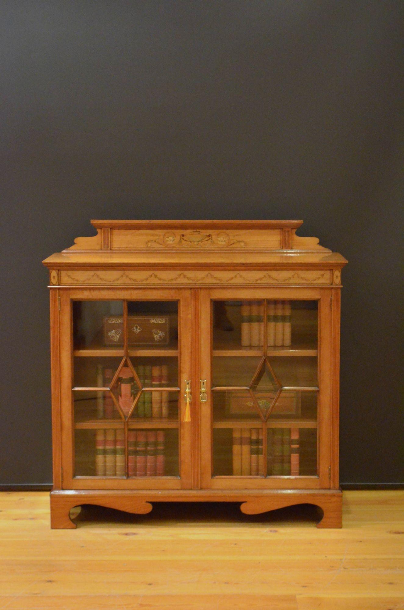 Sn5499 Fine quality and very attractive late Victorian / Edwardian satinwood bookcase or display cabinet, having shaped, inlaid and reeded upstand, well figured top and frieze inlaid with Neoclassical motifs above a pair of astragal glazed door