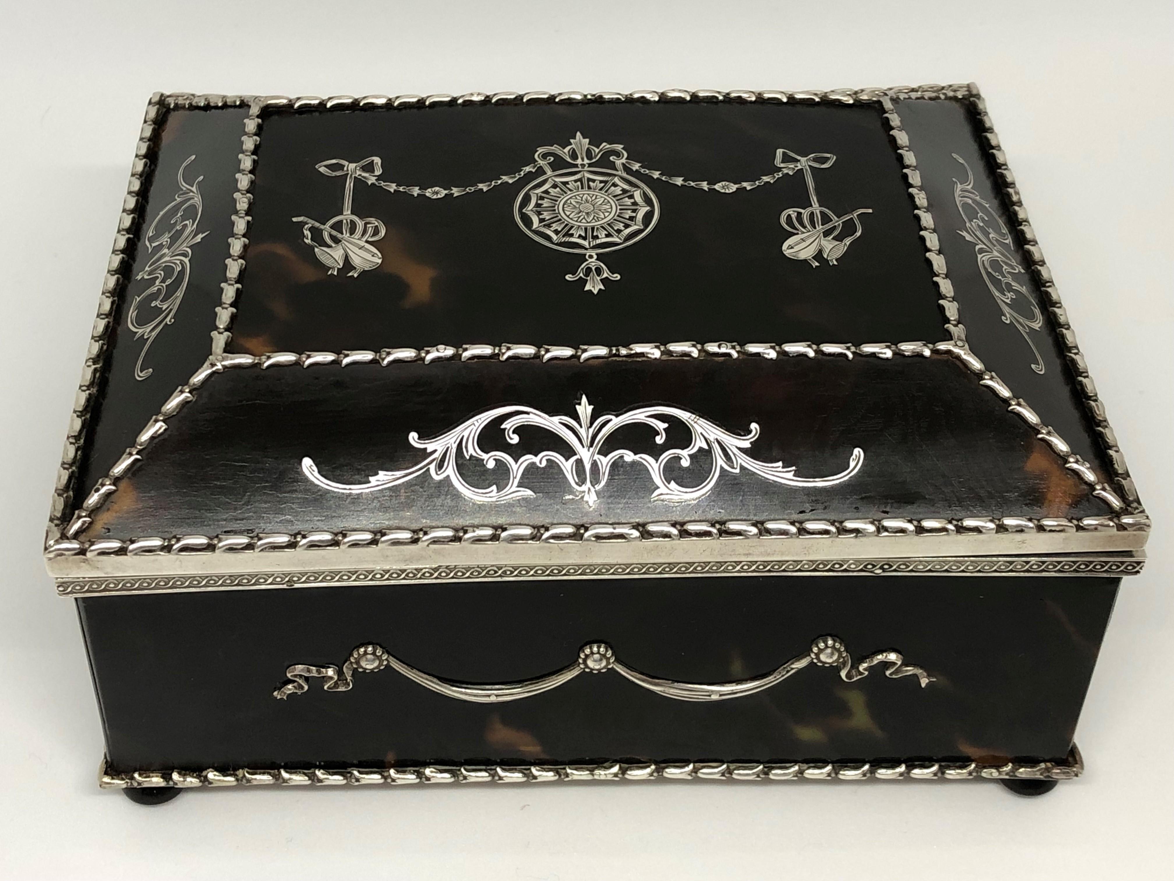 A fine quality Edwardian silver mounted tortoiseshell jewellery casket, inset with silver Neoclassical style pique decoration.

 

The hinged cover opening to reveal a fitted satin lined interior, the base covered with a panel of sterling silver and
