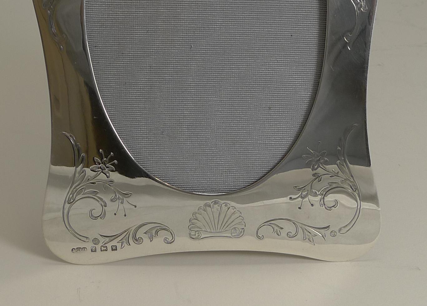 A stunning shaped photograph frame made from solid English sterling silver fully hallmarked for Birmingham 1921, 98 years old. The makers initials are also present for Joseph Gloster Ltd.

The frame is decorated with top quality engraving