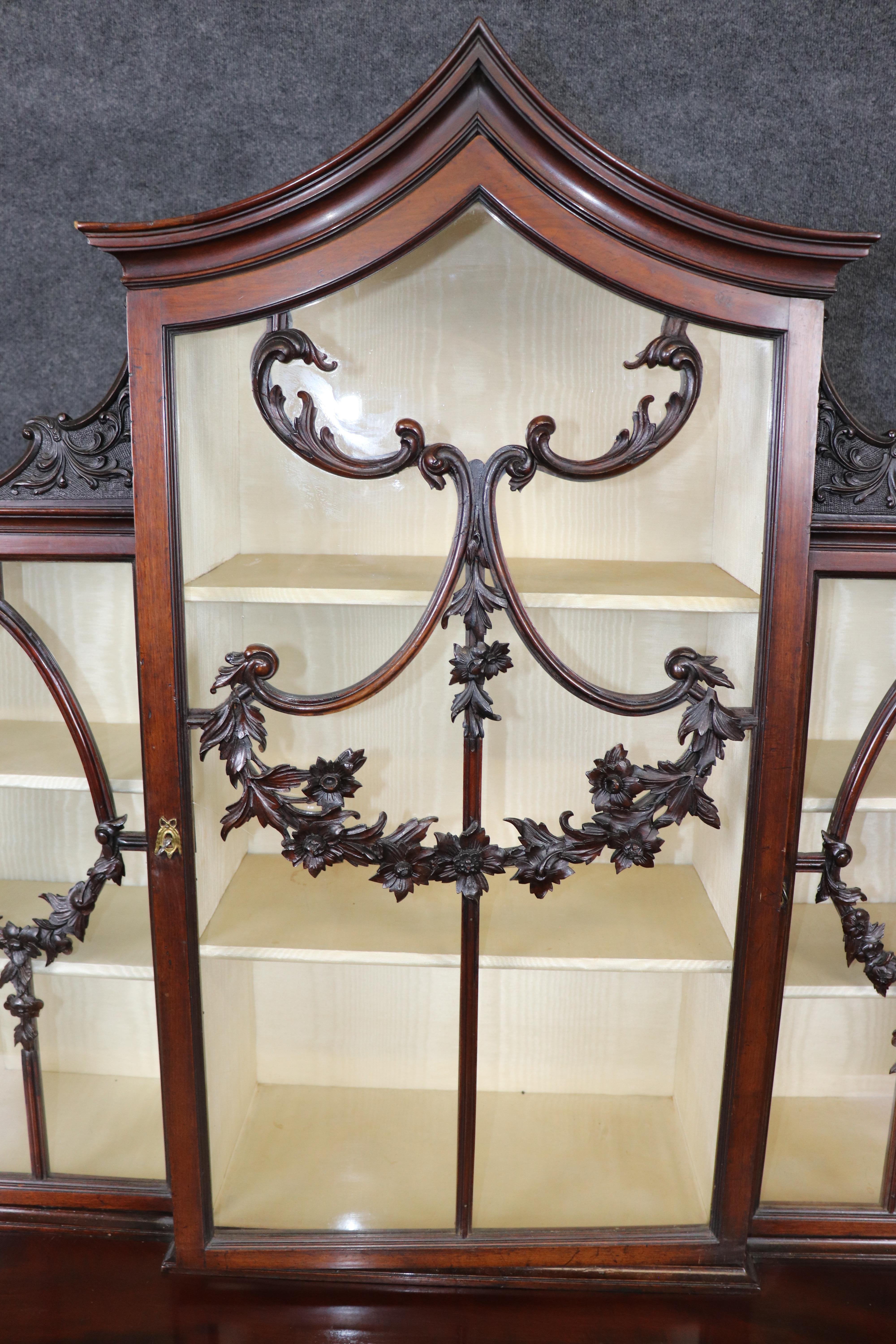 This magnificent English Georgian mahogany display cabinet embodies the grace, symmetry, and craftsmanship that define the Georgian period. Expertly crafted from richly figured solid mahogany, this two-part cabinet features a swan-neck pediment