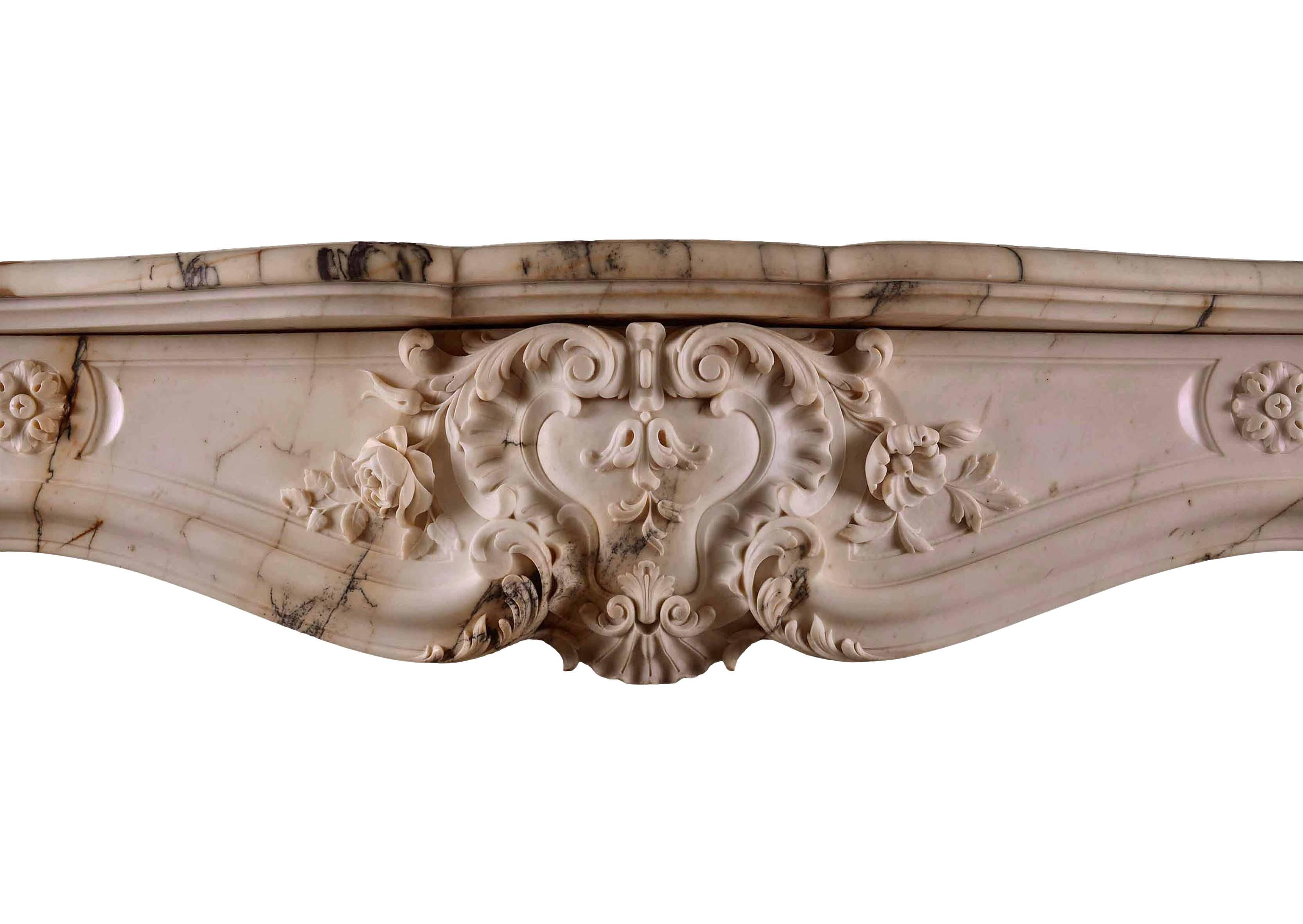 A very fine French Louis XV style fireplace in Paonazzo marble. The panelled frieze with carved central cartouche, foliage and shells, flanked by rosette paterae. The jambs with scrolls to base, surmounted by stiff acanthus leaves, foliage and