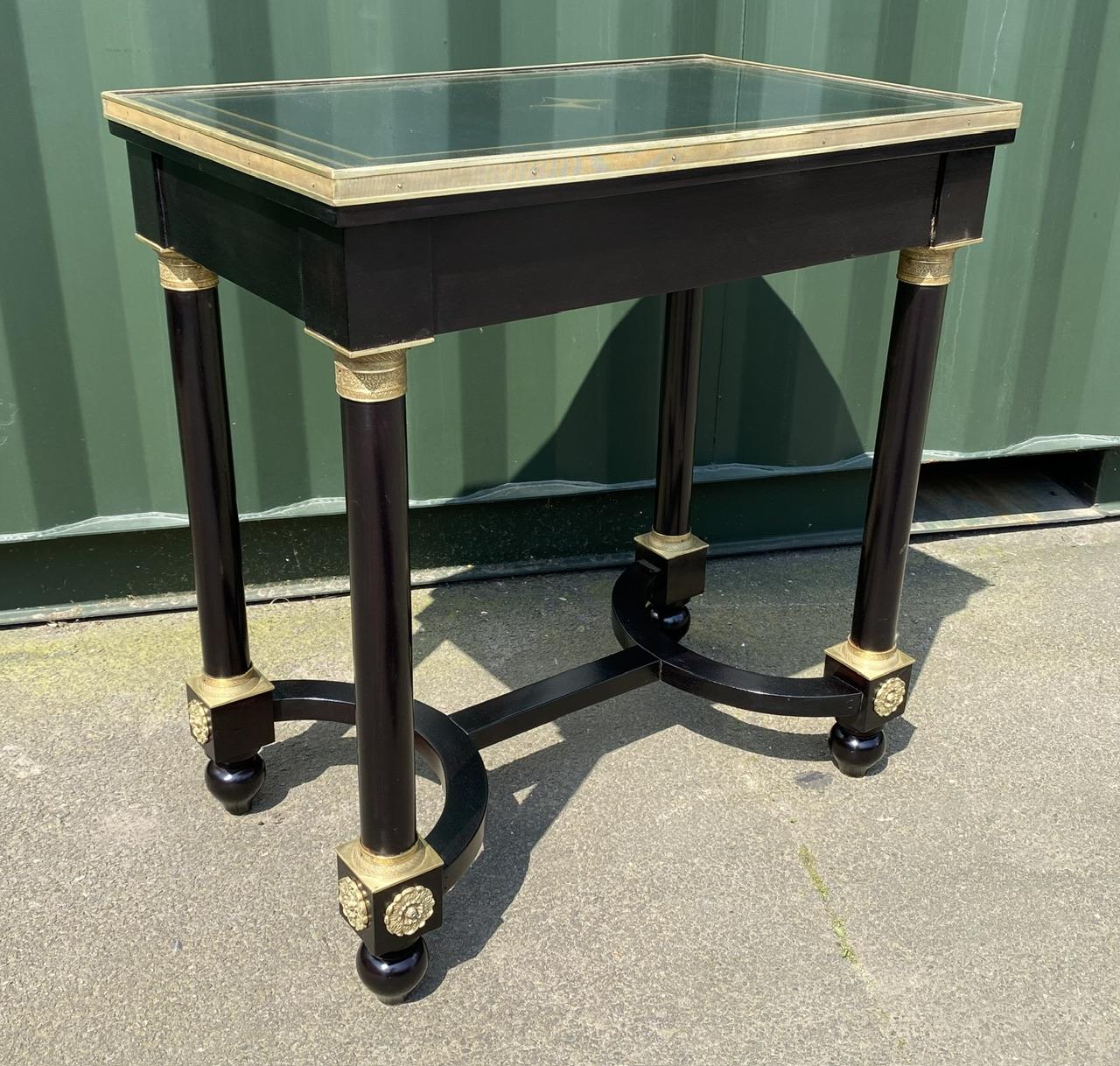 An extremely fine quality French Louis XVI design piece of furniture. Made from Mahogany which is ebonised and having very well cast ormolu brass detailing, the top has a gold painted design with a glass top which is incased by the brass edging. The