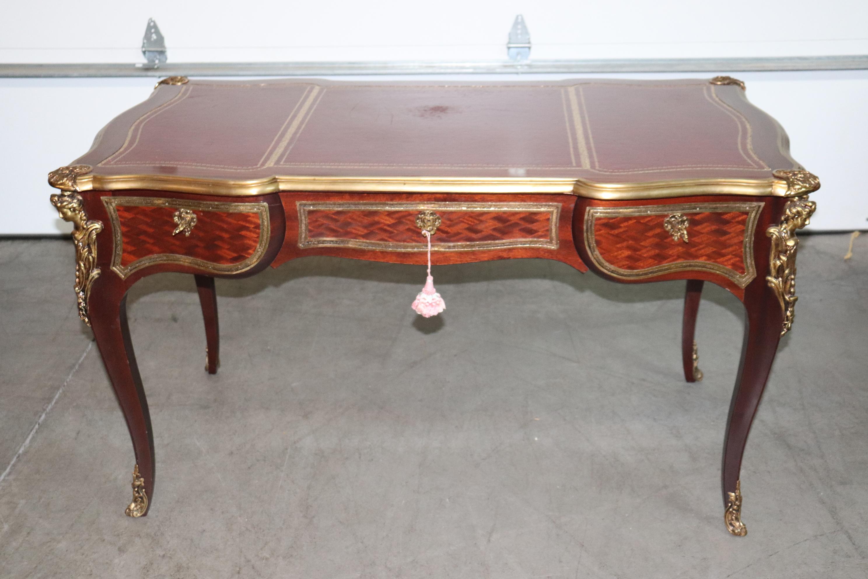 This is a fine quality French-made bronze mounted and trimmed writing desk. The desk features gorgeous bronze trimmed wrap around moldings around the top and highly detailed bronze maidens on each corner. The desk also features beautiful mahogany