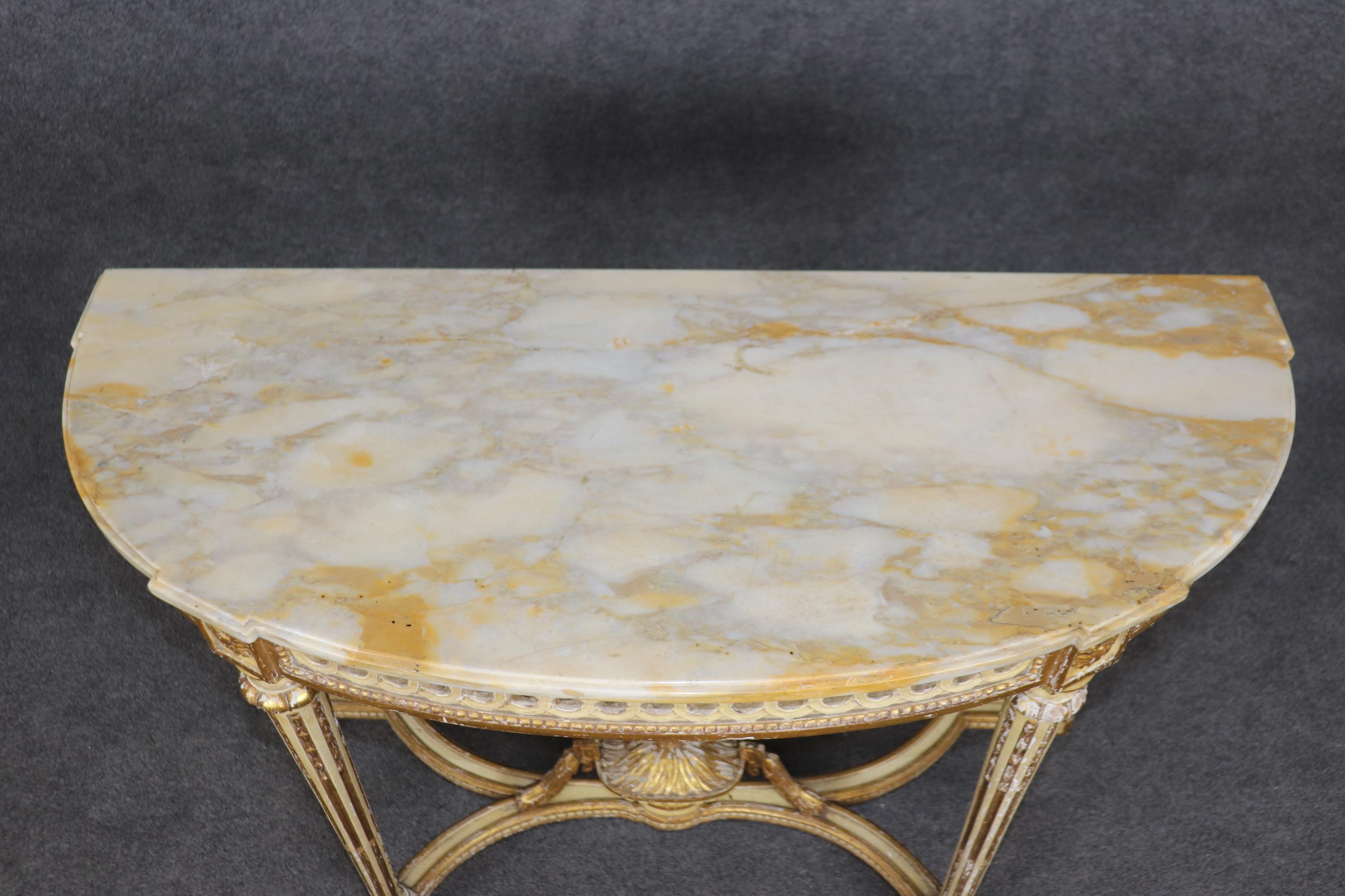 This is a classic and stunning distressed from time, gilded and painted console or demilune table with a fine marble top. The table is in its original fiinsh and would be considered good original condition. Measures 35.25 tall x 46.5 wide x 19