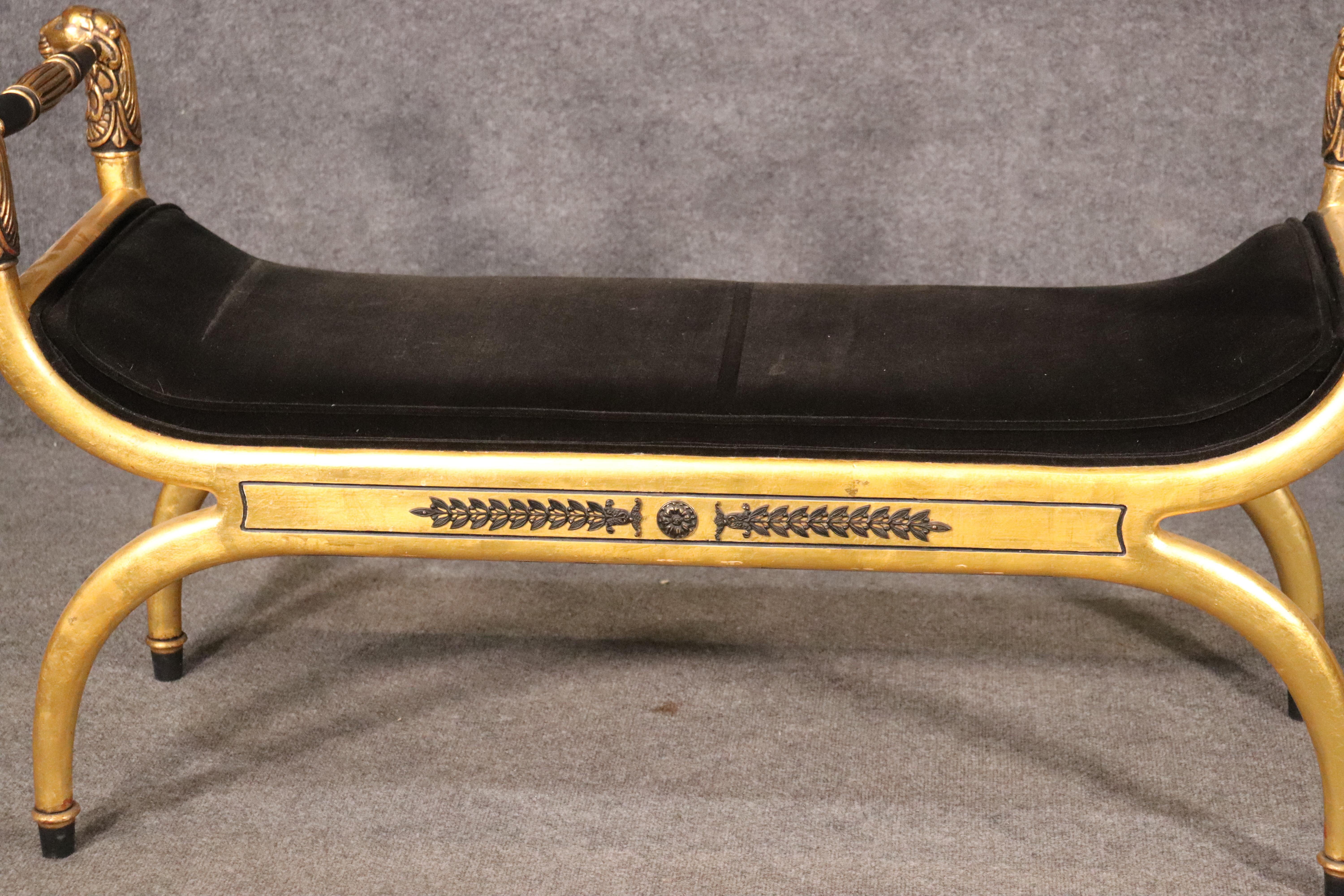 This is a fine luminous gold leafed and bronze mounted lion carved French or perhaps alternatively Hollywood Regency window bench. It will work with both design schemes. The gold leaf is bright and beautiful and the upholstery appears to be a high