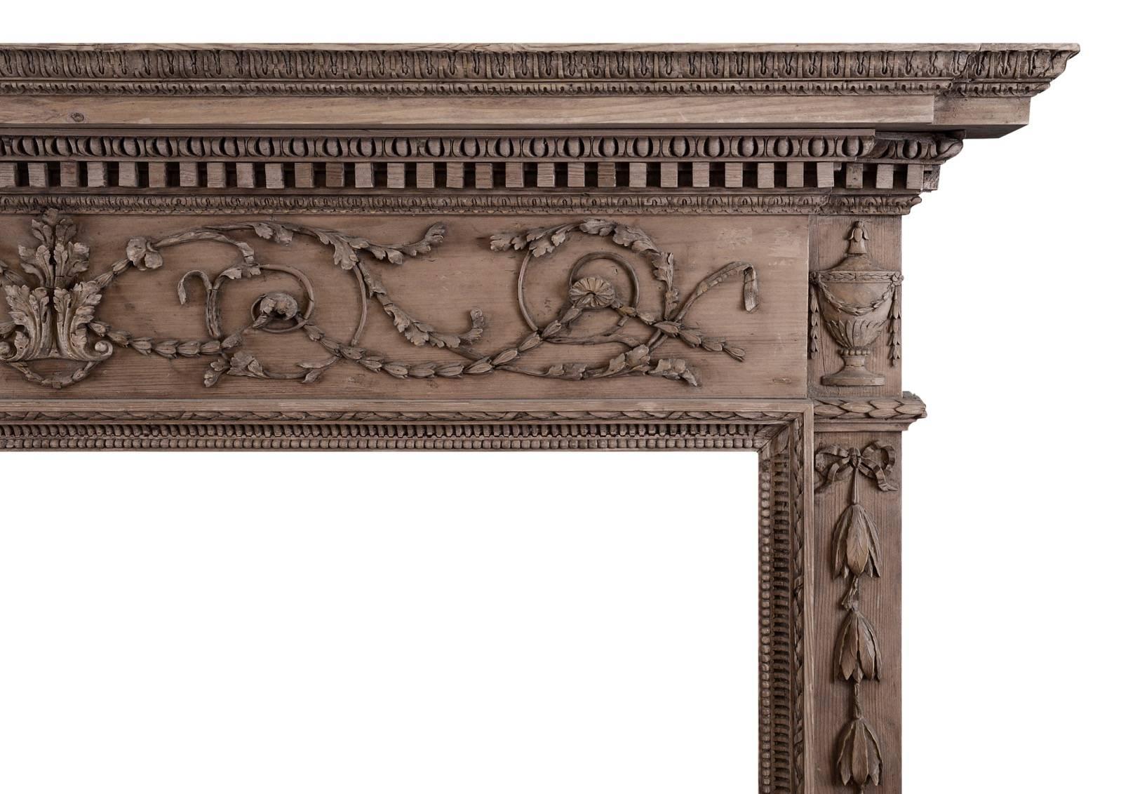 A fine quality late Georgian carved pine fireplace. The frieze with delicate carving of acanthus leaf central motif leading to flowing scrolled foliage and paterae. The jambs with tied ribbons and bellflower drops, carved leg moulding with beading,