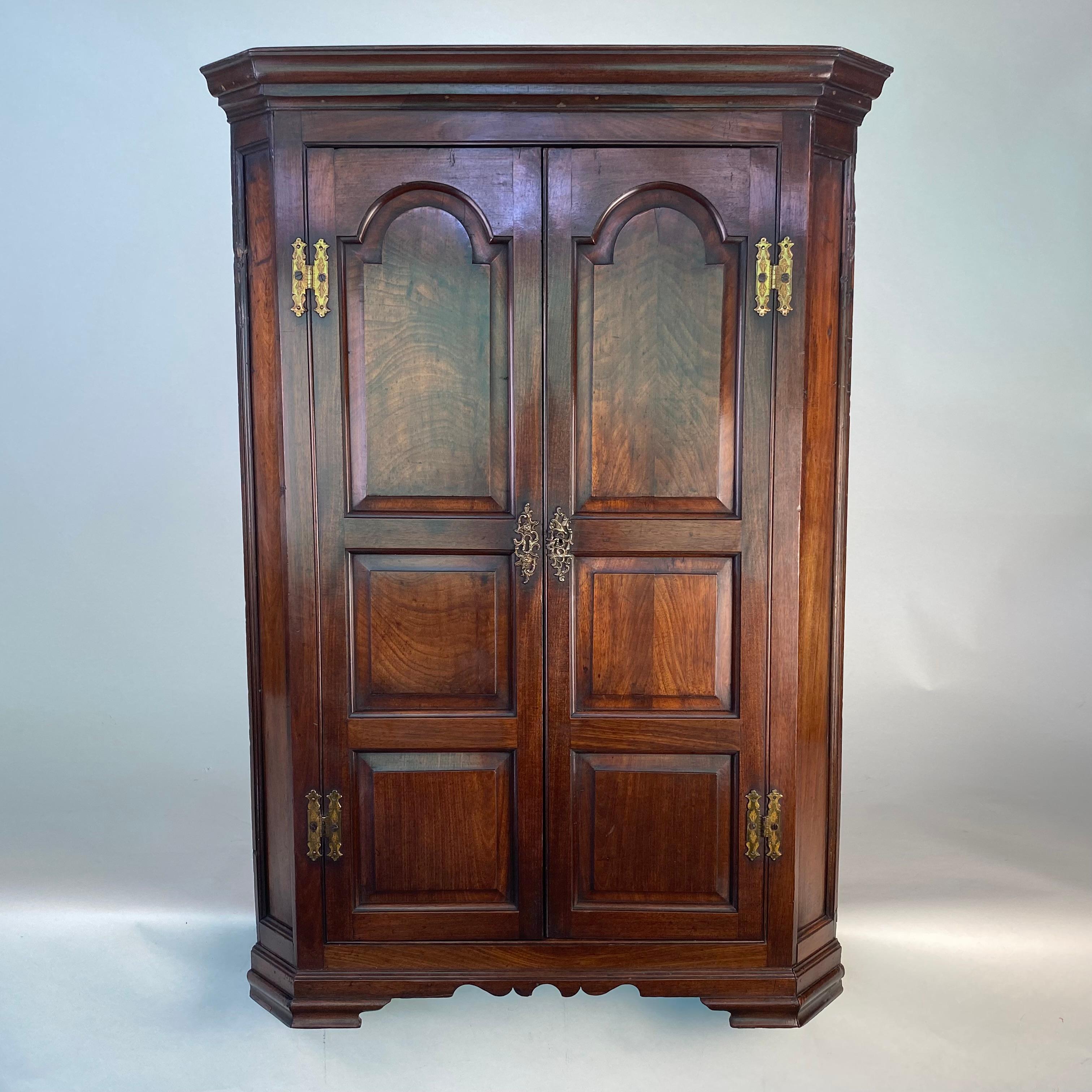 A very fine quailty George III period mahogany hanging coner cupboard.  The two doors each constructed with and arch-top fielded panel above two further fielded panels and flaked by canted side panels wth moulded cornice above and a shaped apron
