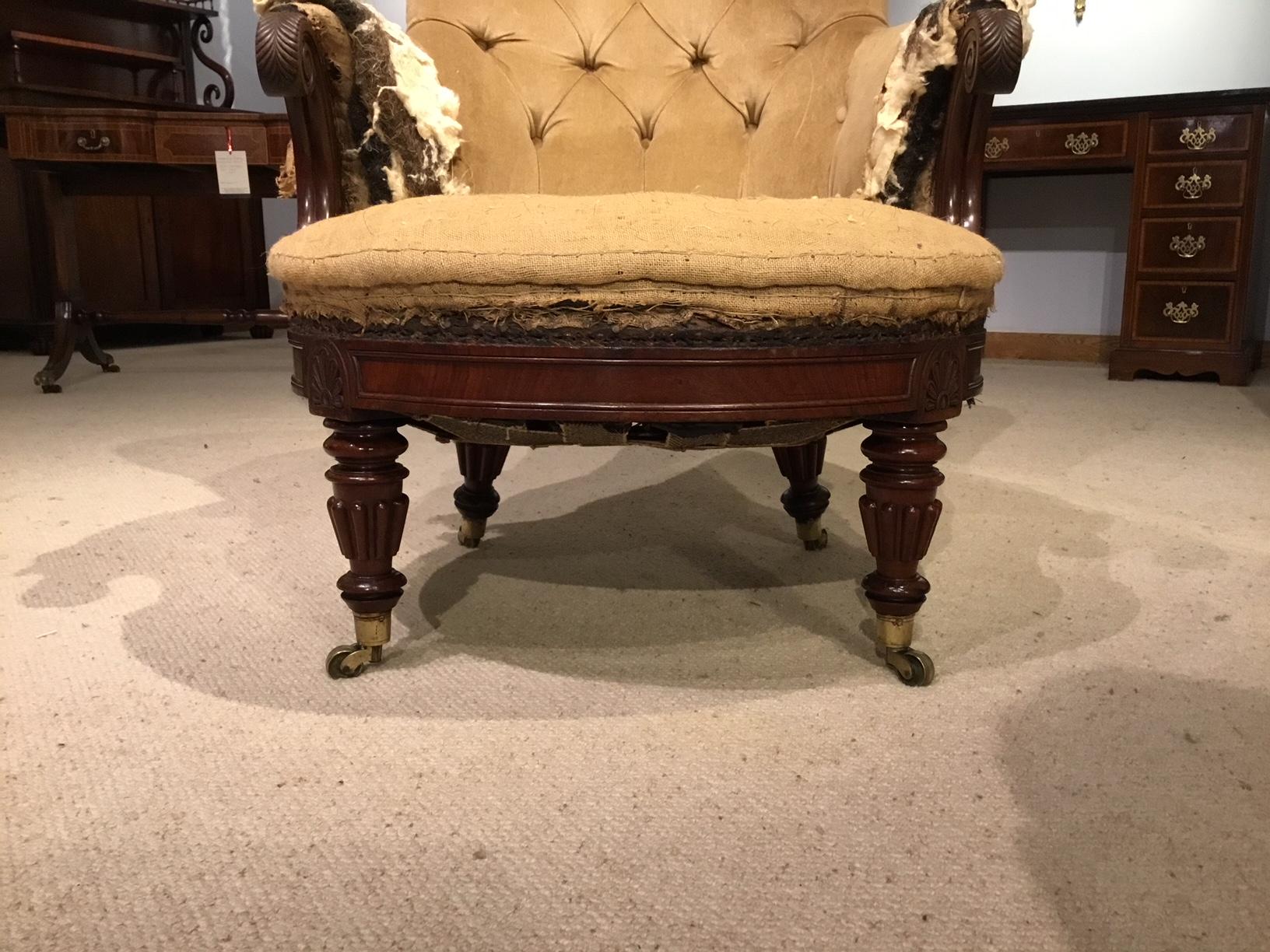 A fine quality mahogany Regency period library chair by Gillows of Lancaster. The deep buttoned back with rolled arms and finely carved knuckles, with a generous sprung seat. Supported on four finely turned and reeded supports with brass cup castors