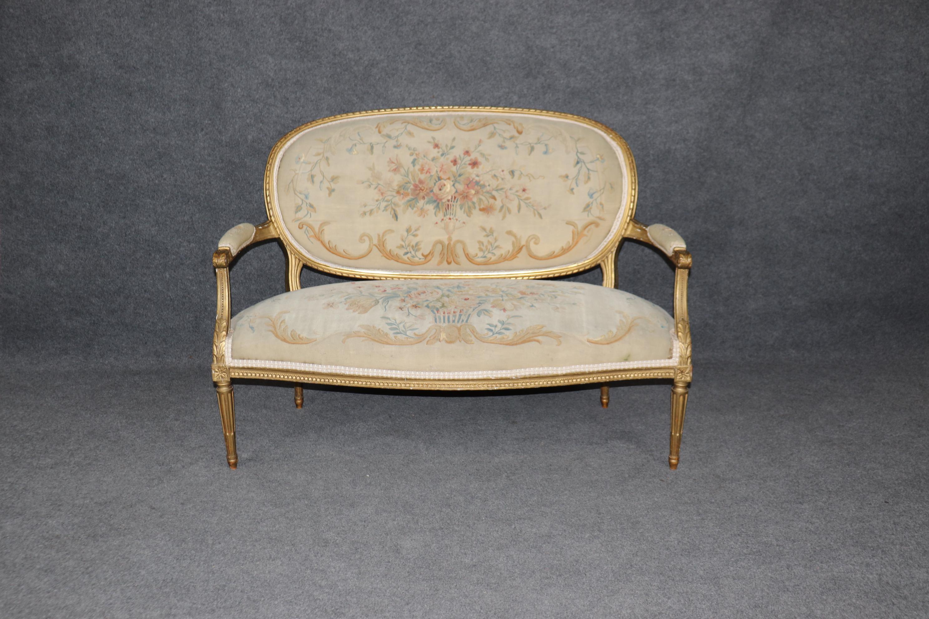 Si tratta di uno splendido divano francese con schienale ovale in legno dorato, risalente al 1900, che presenta una finitura in legno dorato invecchiato e una bellissima tappezzeria originale a fiori Aubusson. La cornice presenta segni di usura e