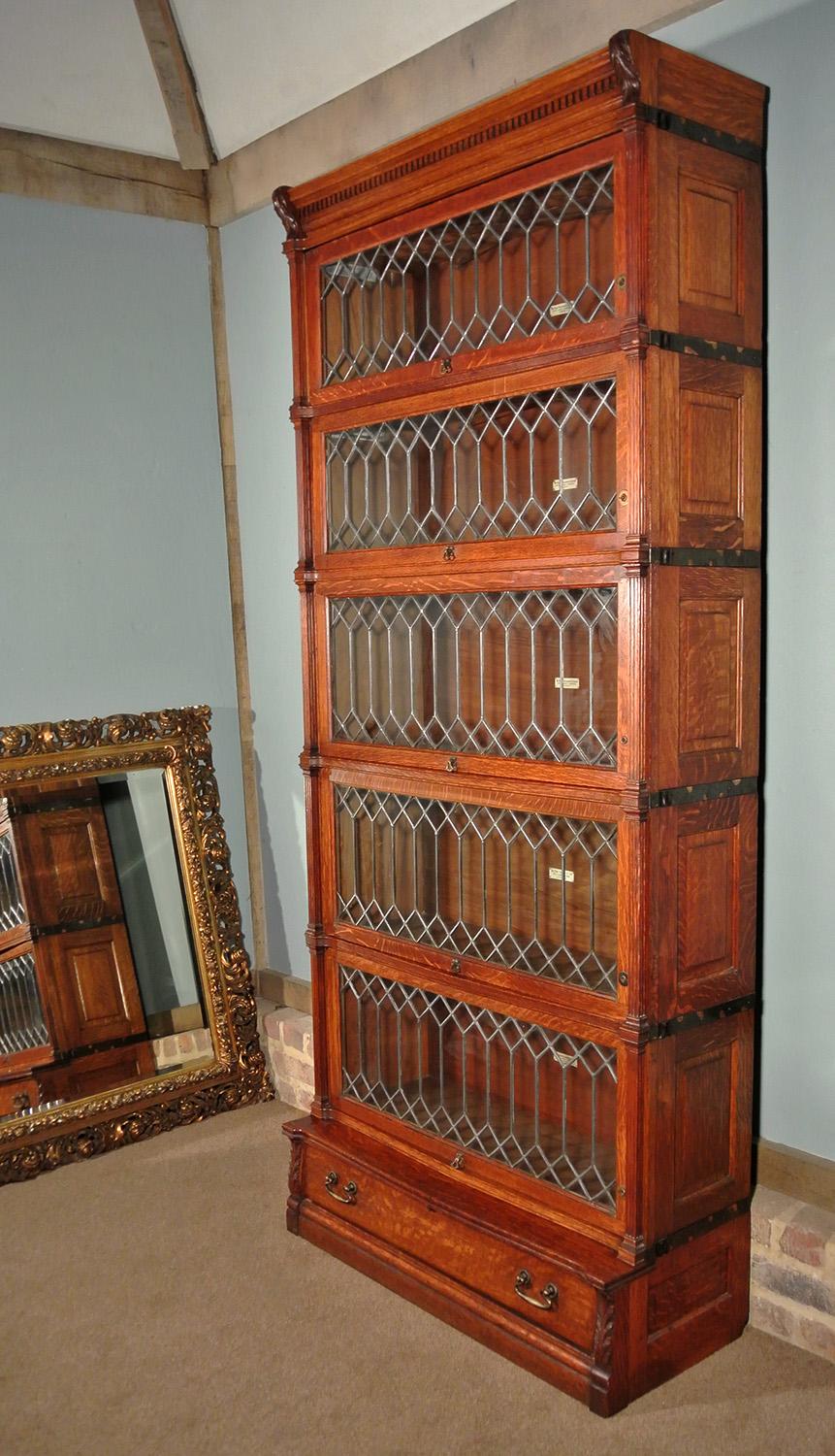A high quality Globe Wernicke bookcase with five original stages all retaining their Globe Wernicke labels, original leaded glass sliding doors with original handles.  Solid well figured oak, the reeded columns with attractively carved acanthus leaf