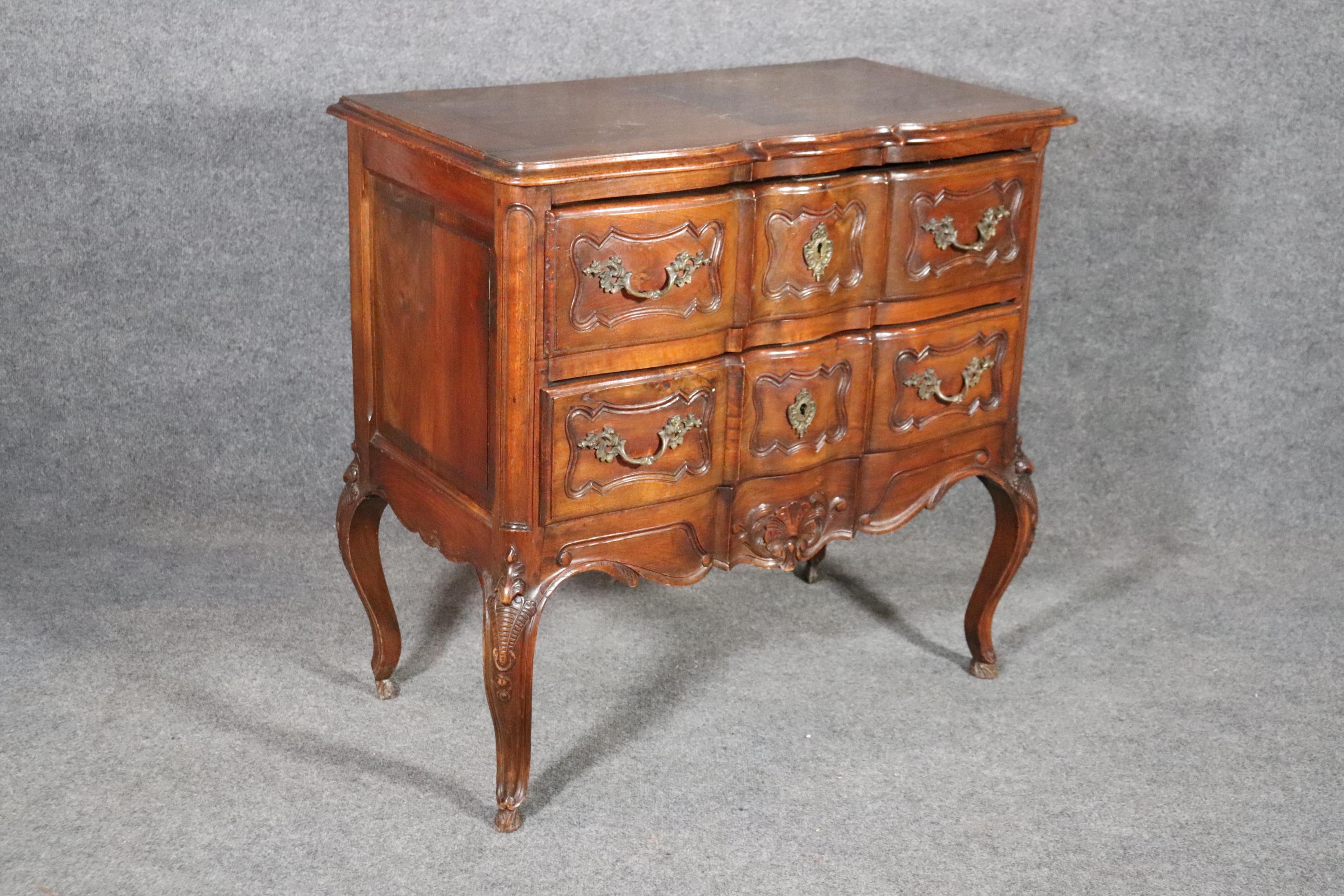 This is a handmade carved walnut French country commode. The piece dates to the 1920s era and is in good condition with minor scuffs and signs of use but nothing significant to mention. The commode does have age cracks as with most European antiques