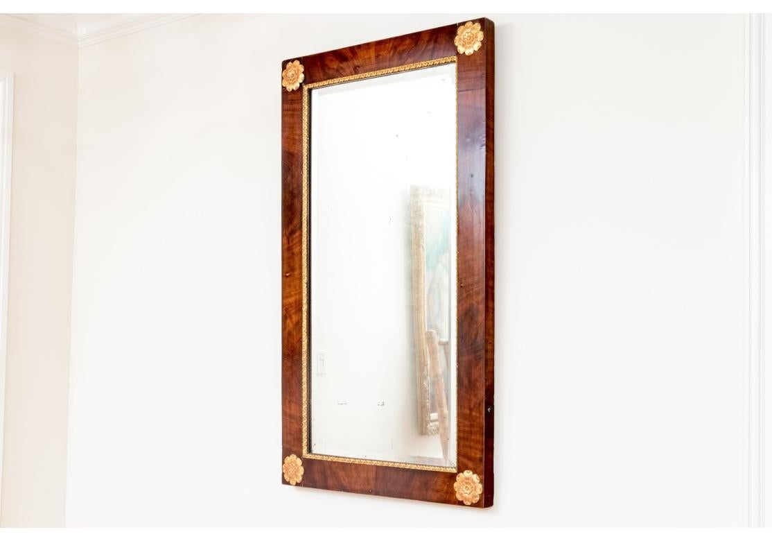 Mahogany frame with beveled mirror plate with decorative carved and gilt finished trim with corner floral appliqués in relief to each corner.

Dimensions: 28