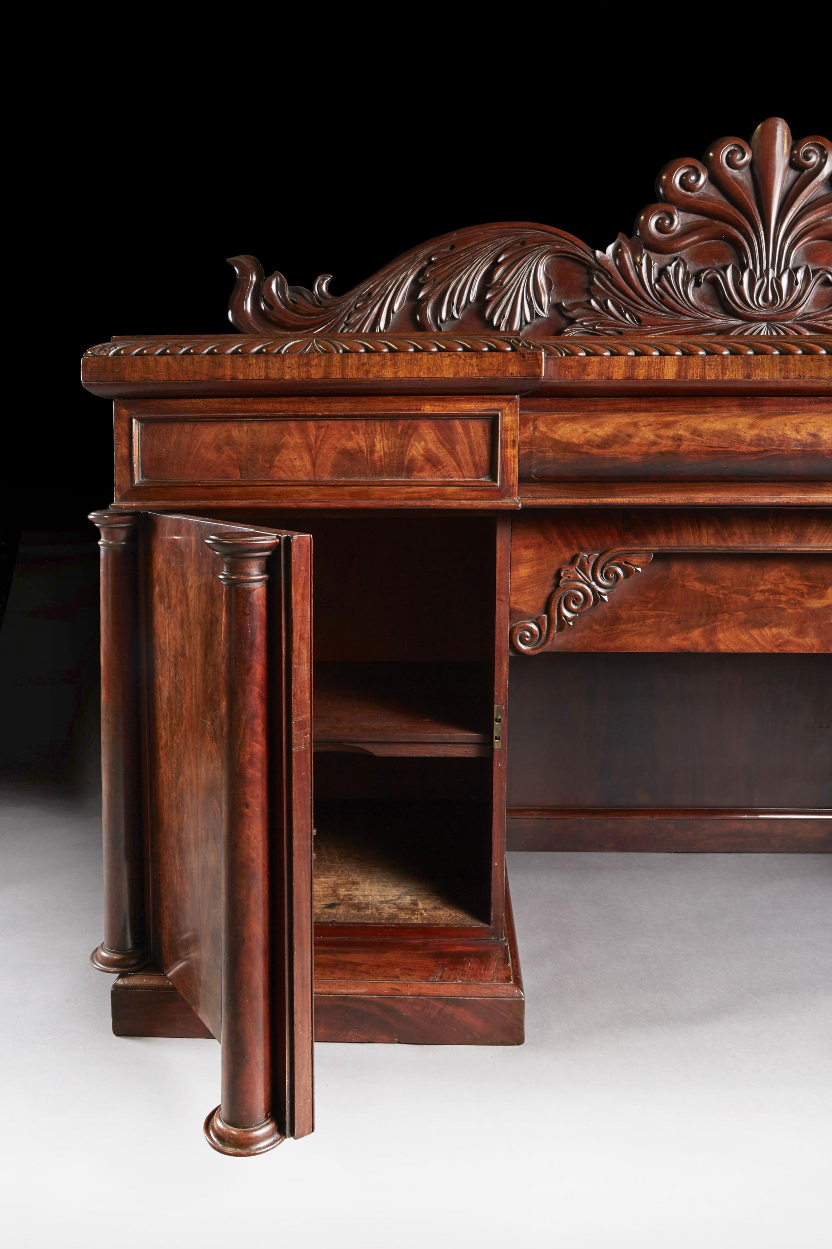 A fine quality William IV flame mahogany inverted breakfront sideboard of good color. 



English, circa 1835



The raised carved back having a central anthemion cartouche, flanked by sweeping carved acanthus leaves over a finely figured