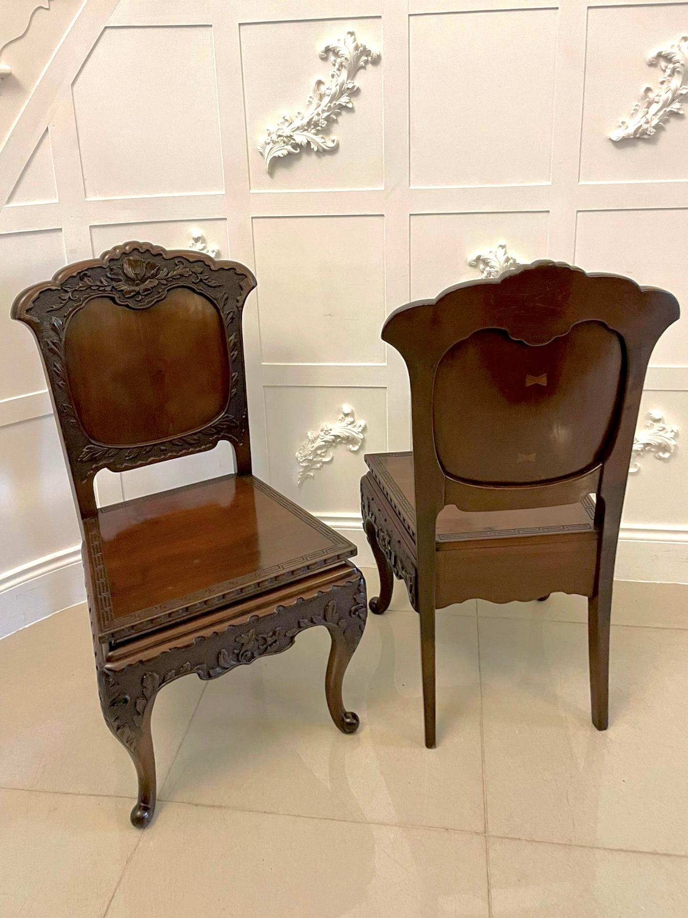 Fine quality pair of antique hardwood carved Chinese hall chairs having finely carved panelled fronts depicting a flower and leaf design. The attractive carved front rail depicts the same leaf design. The carved and shaped back boasts two bow inlays