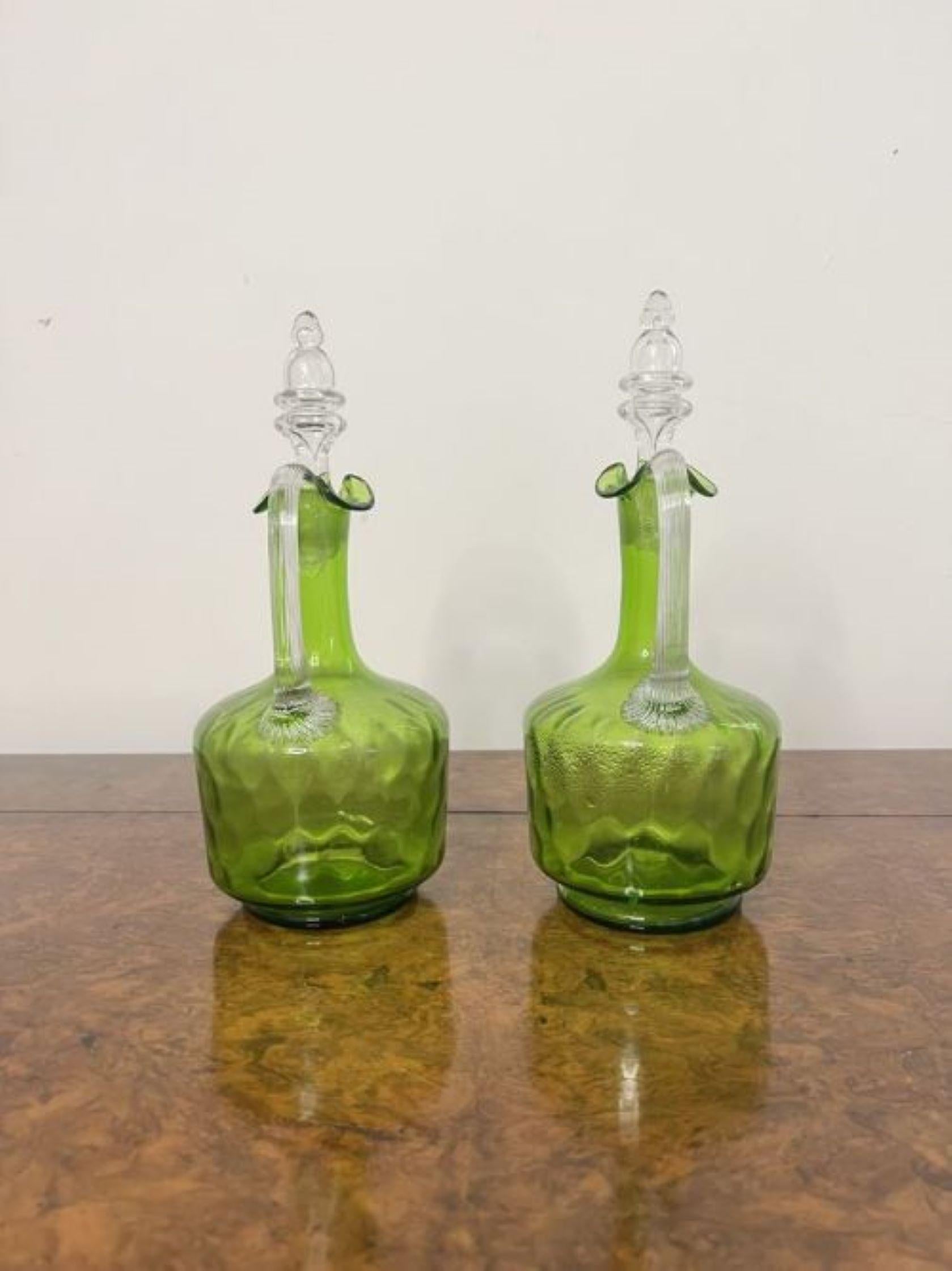 Fine quality pair of antique Victorian green glass decanters having a quality pair of green glass decanters, with a shaped handle to the back a wavy neck to the top with the original stoppers. 