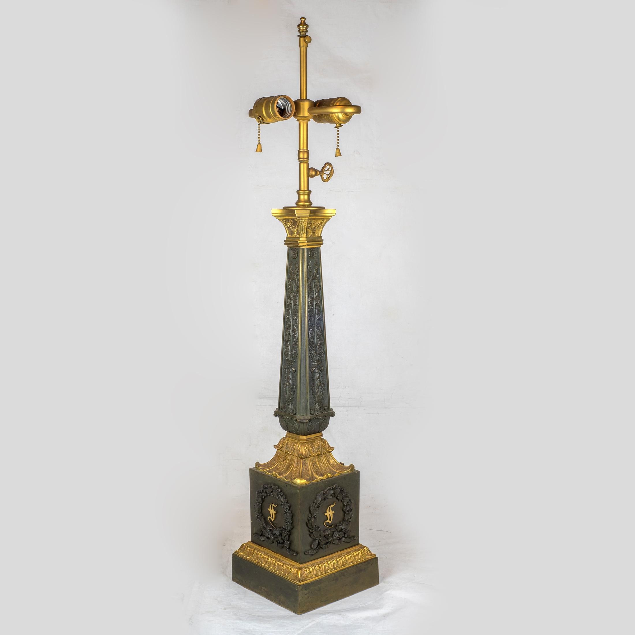Paire de lampes très décoratives en bronze doré et bronze patiné de style Empire français du XIXe siècle, sur base carrée. Chacune des quatre faces de la base est ornée d'un motif de récif. Le reste de la lampe est recouvert de scènes