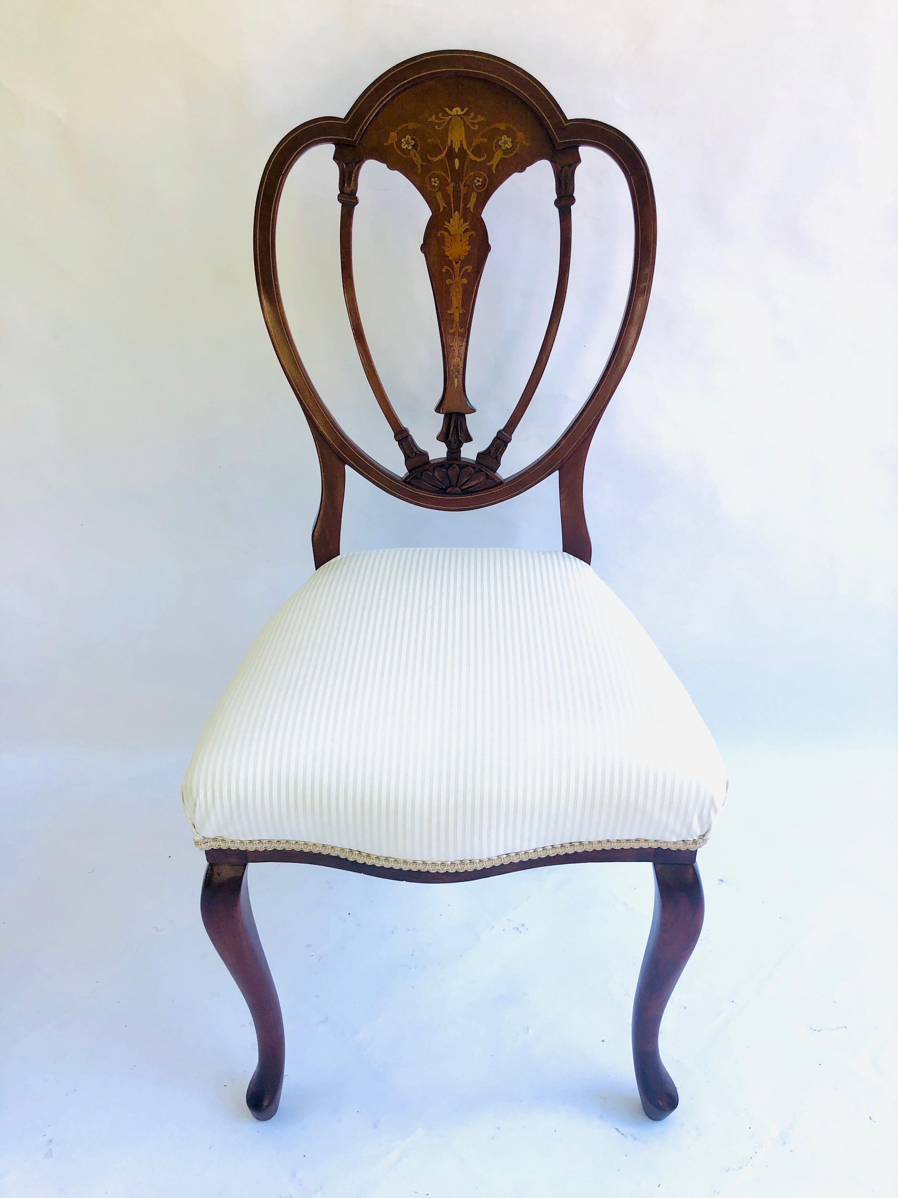 Fine quality pair of antique inlaid mahogany Victorian side chairs having an exquisite marquetry inlaid shaped back with an inlaid marquetry center splat. They have elegantly shaped cabriole front legs and out swept back legs. They have both been